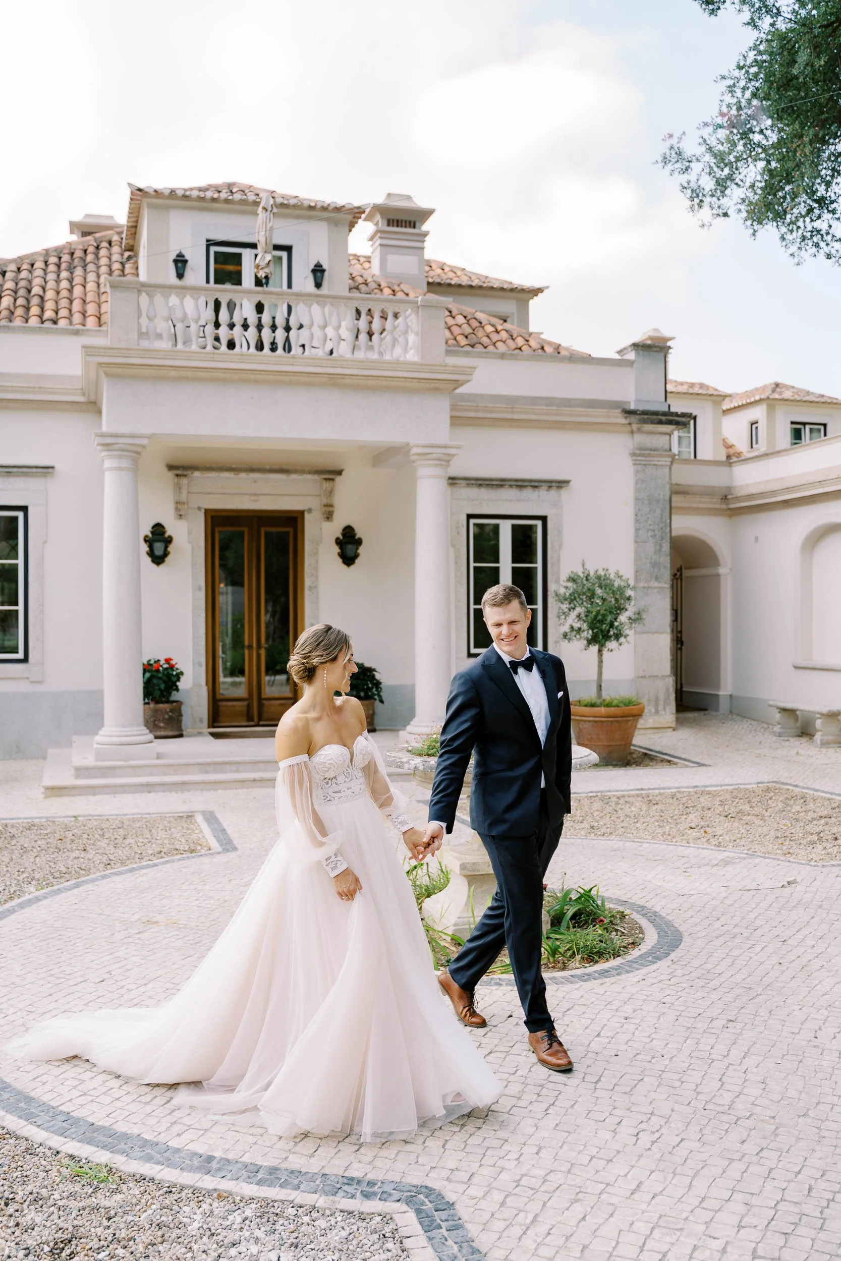 Bride and groom walking in front of the palace at Quinta da Bella Vista in Sintra, Portugal