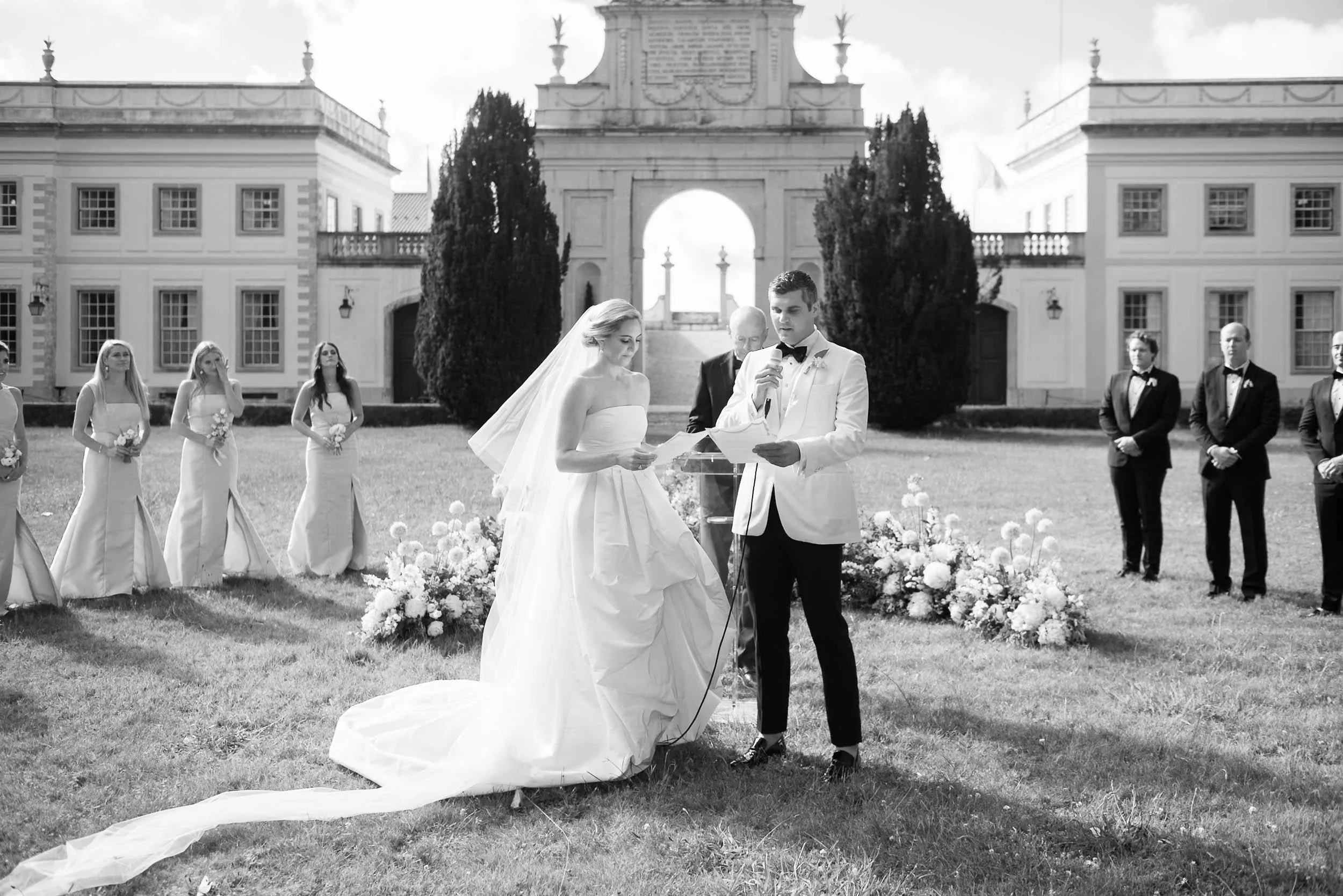 A black-and-white photo of a wedding ceremony outdoors with a bride and groom at the altar at Palácio de Seteais in Sintra