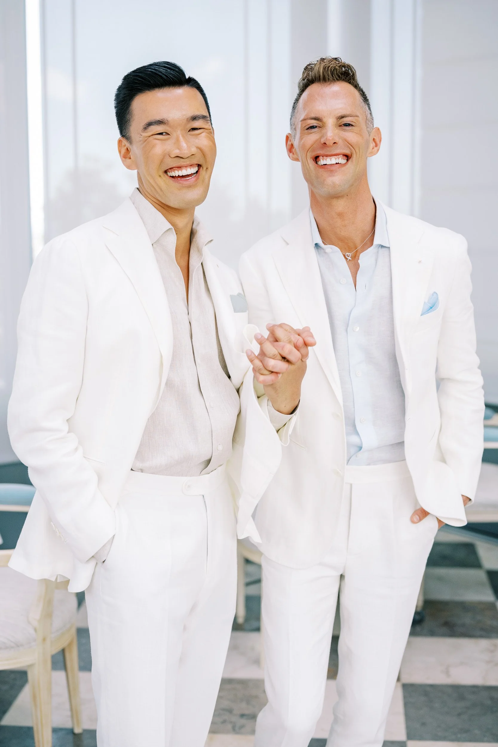 Two grooms holding hands and smiling
