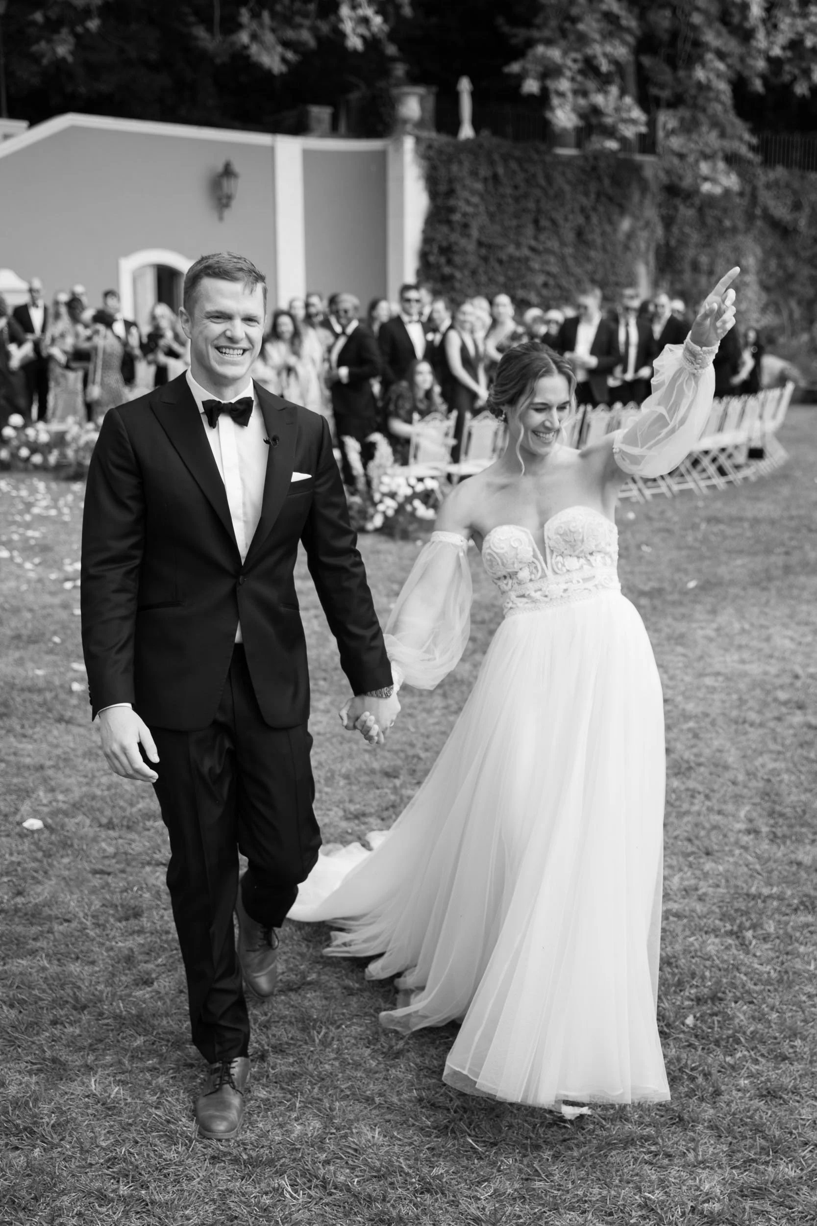 Happy bride and groom leaving the ceremony with guests in the background at Quinta da Bella Vista in Sintra, Portugal