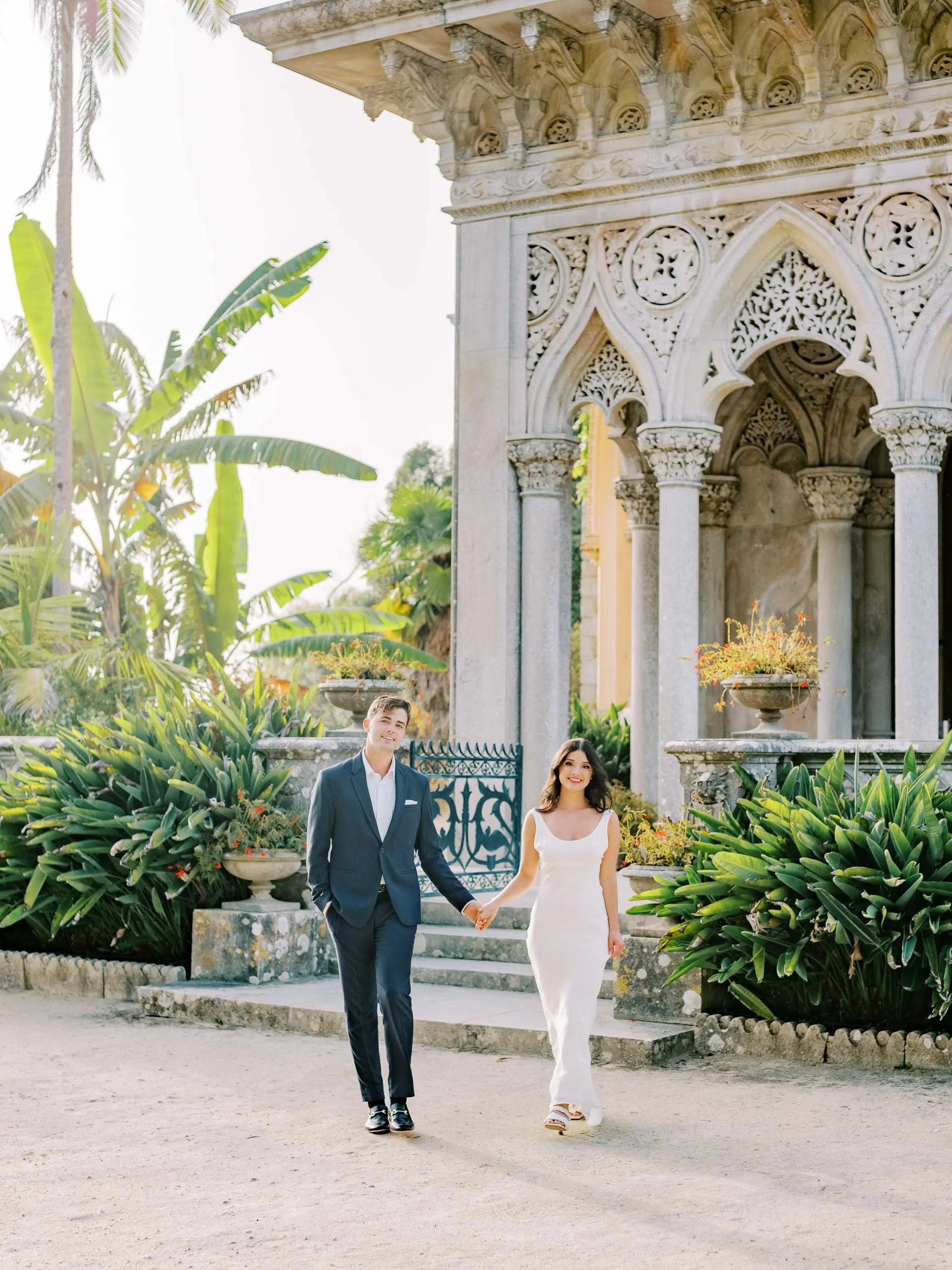 Bride and groom walking in front of the Palace of Monserrate in Sintra