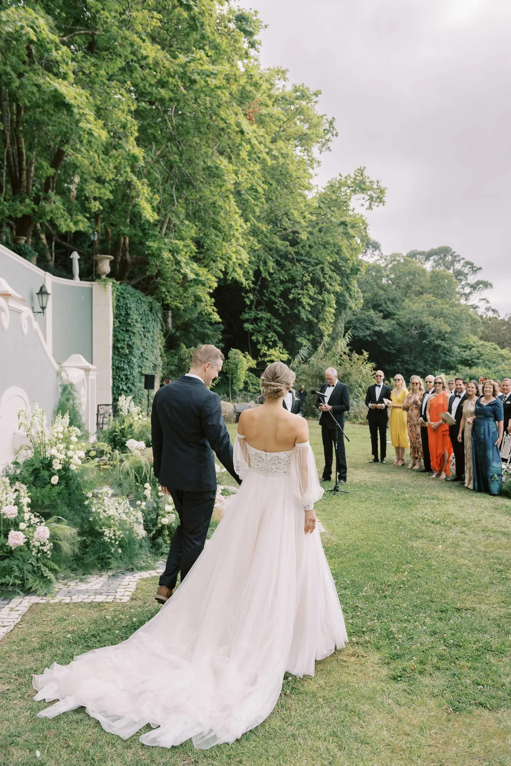 Bride and groom arriving at cocktail hour with guests waiting ahead at Quinta da Bella Vista in Sintra, Portugal
