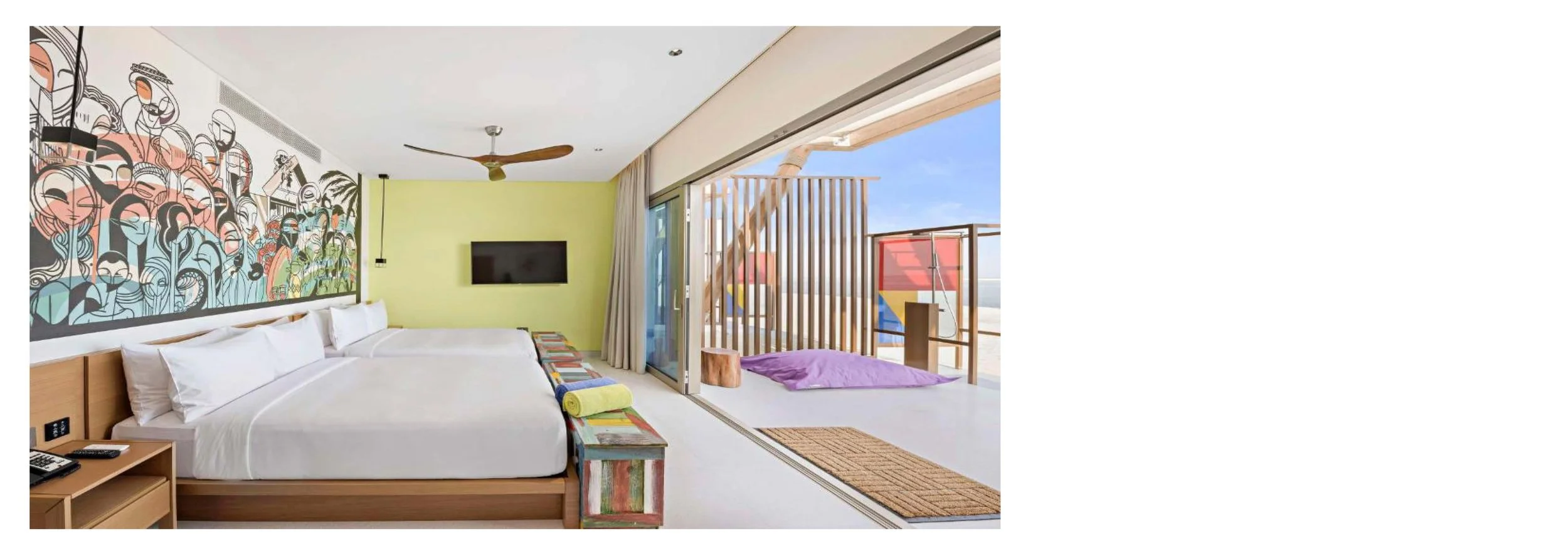 A modern hotel room with two beds, colorful artwork on the wall, a flat-screen TV, and a balcony with a view outside.