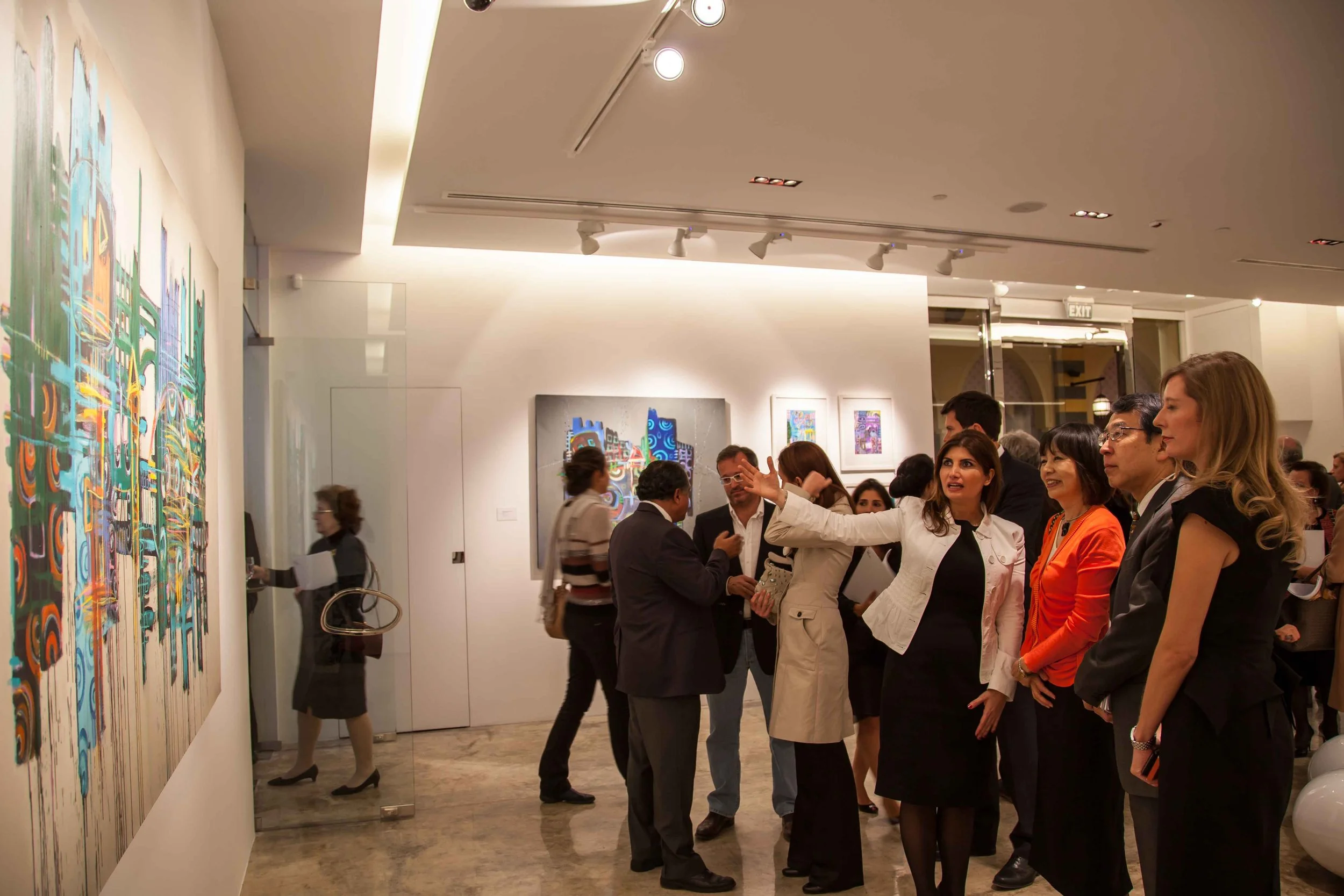 Gallery opening with people observing colorful abstract paintings, some engaging in conversations, in a well-lit art gallery.