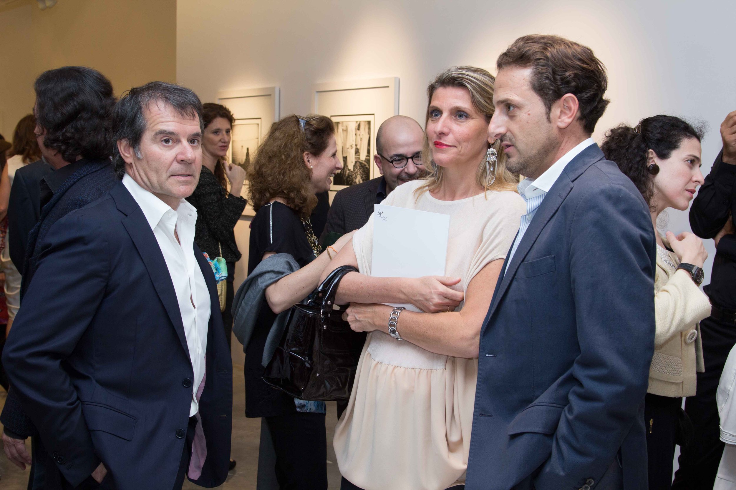 Group of people at an art gallery exhibition, engaging in conversation.