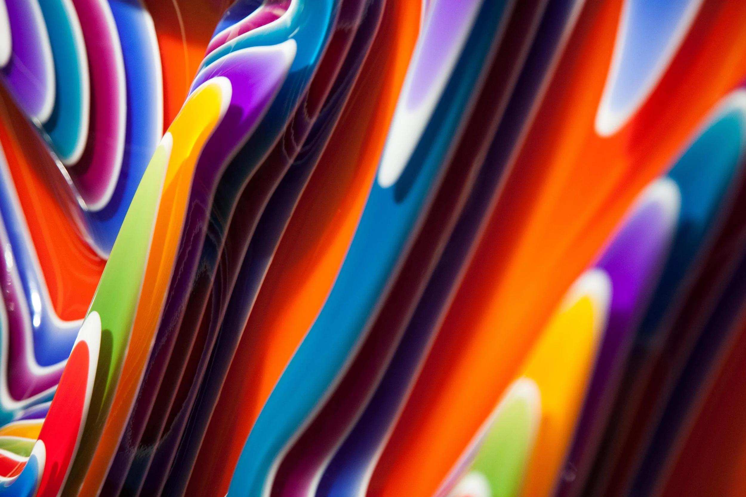Close-up of colorful, stacked surfboards with vibrant colors and glossy surfaces.