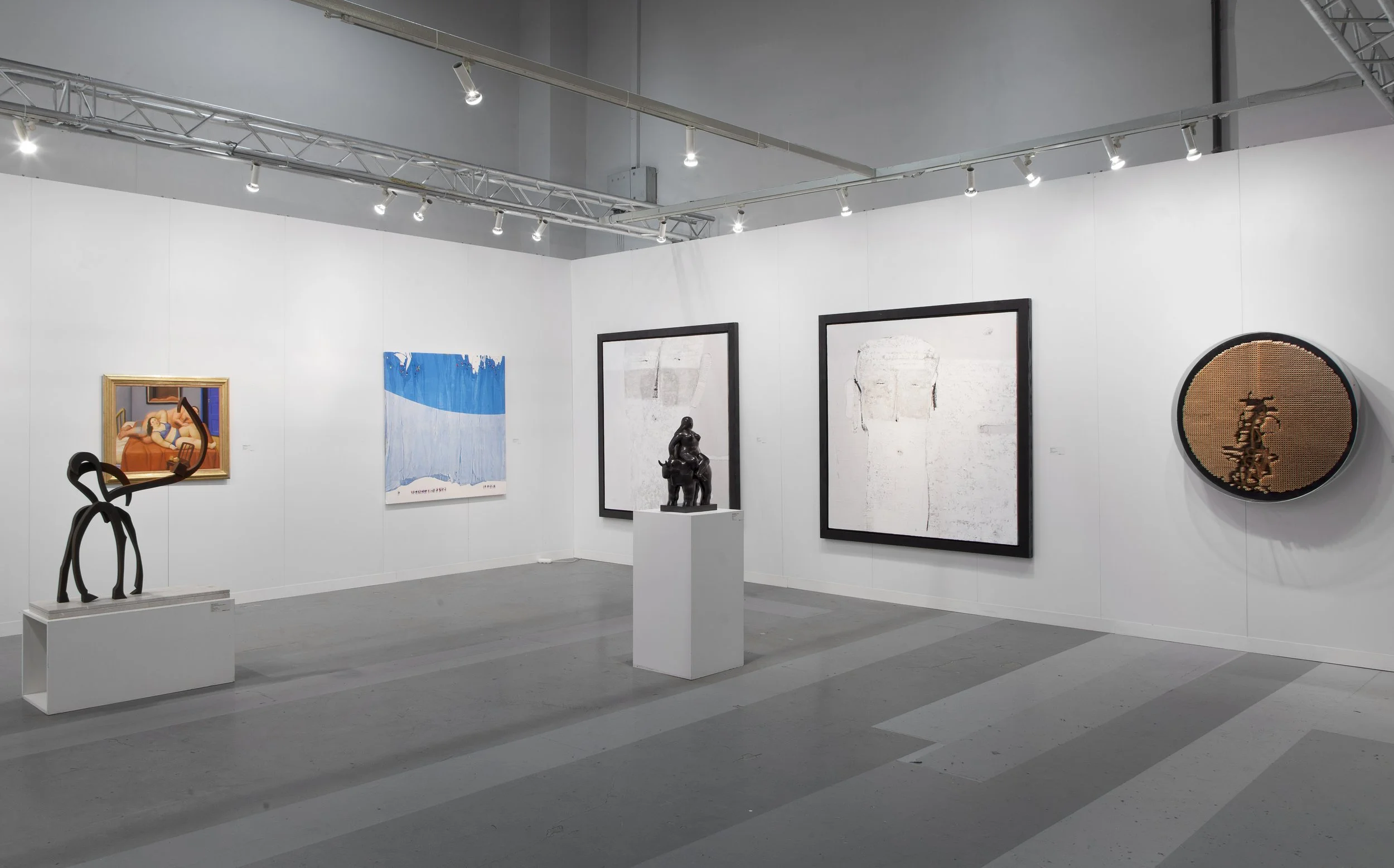 Art gallery with paintings and sculptures displayed on white walls and pedestals, including abstract, figurative, and modern art pieces.