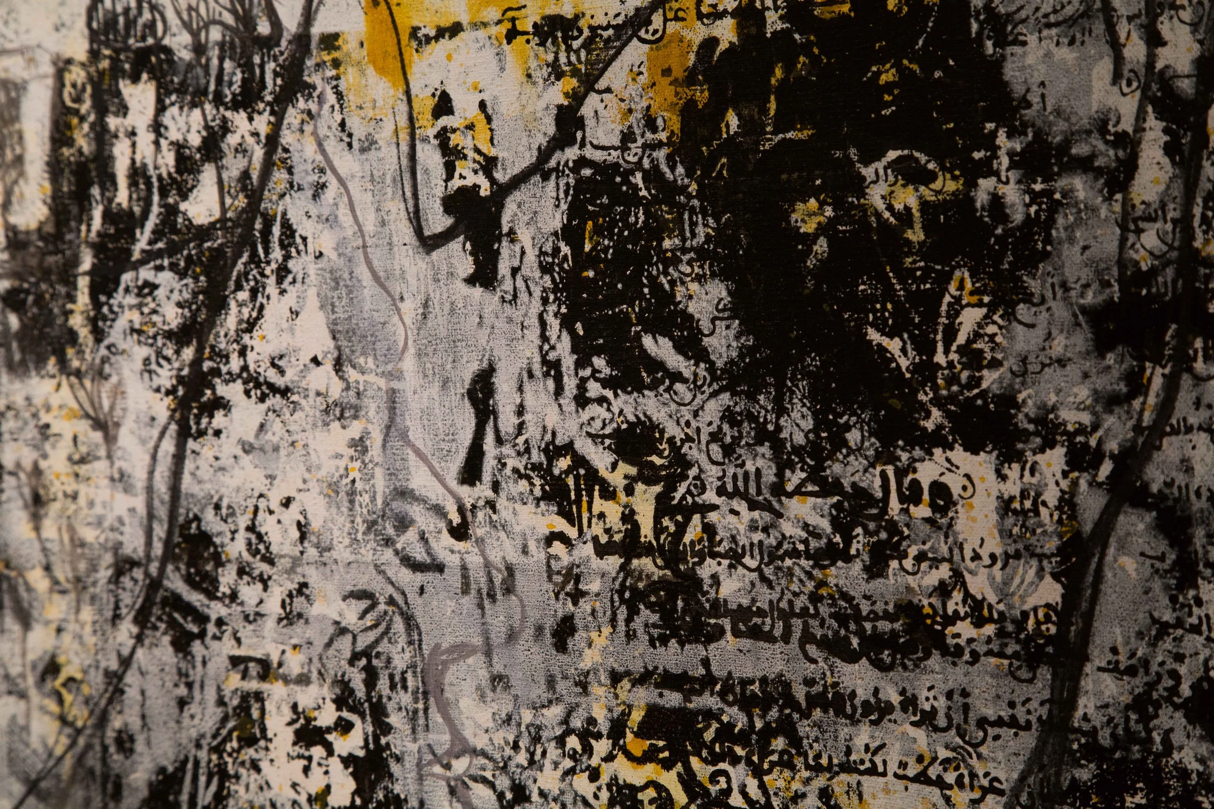 Close-up of an abstract black and gray painting with yellow accents and intricate patterns and lines.