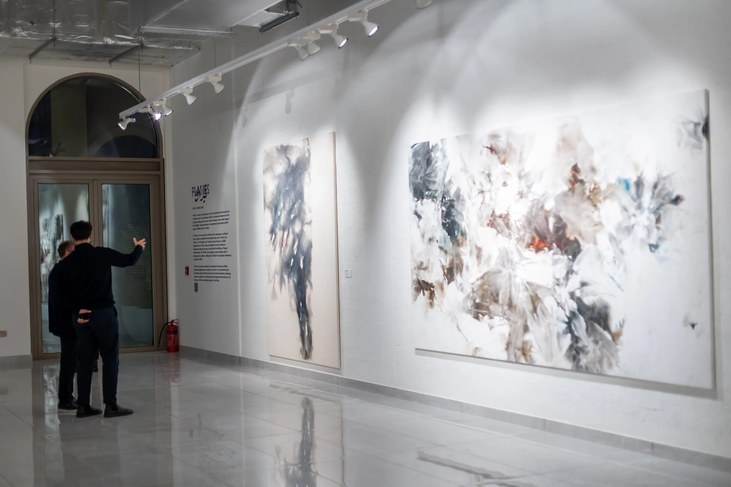 People viewing abstract paintings in an art gallery.