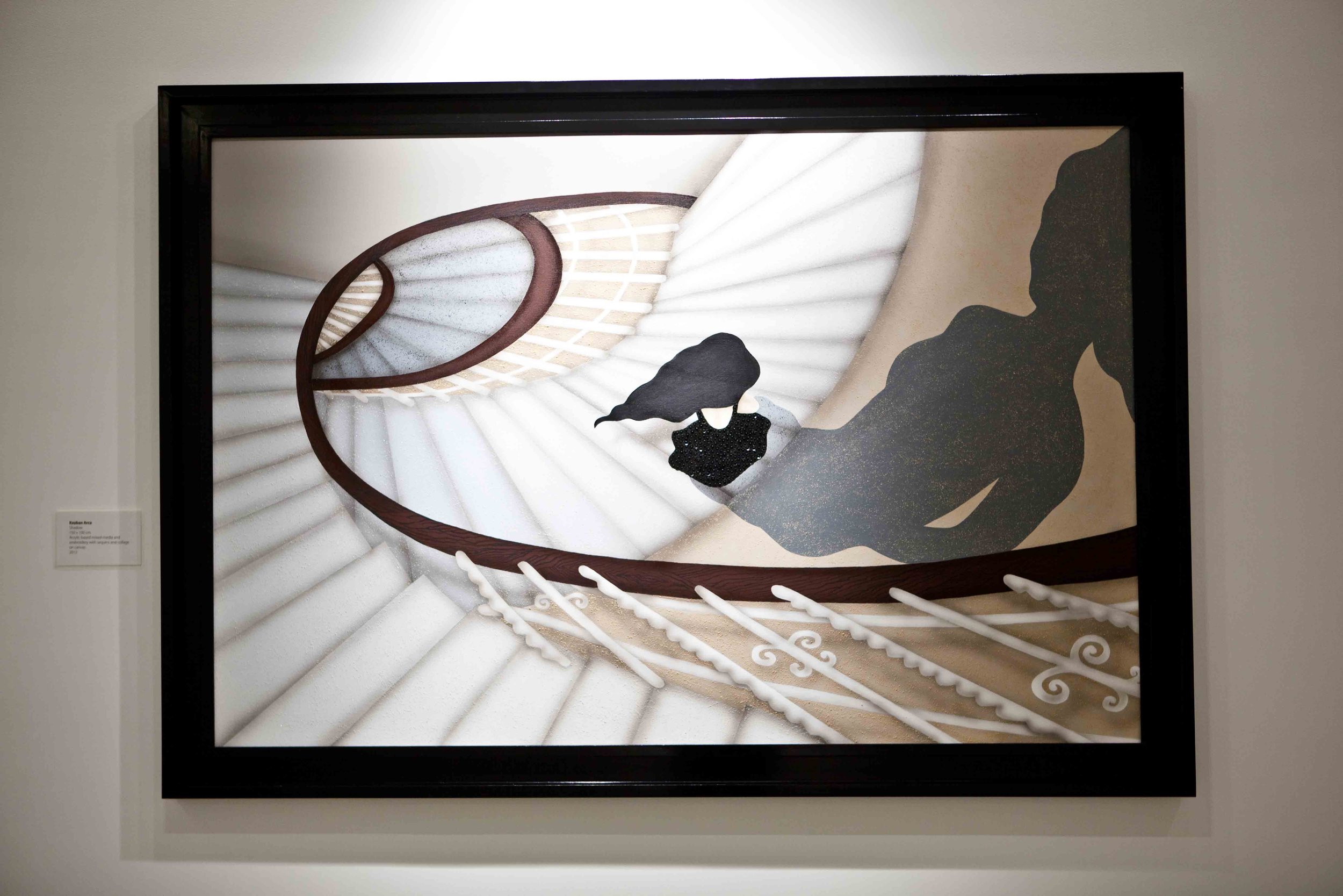 A spiral staircase viewed from below with a woman in a black dress, black hair, and a person in dark clothing ascending the stairs.