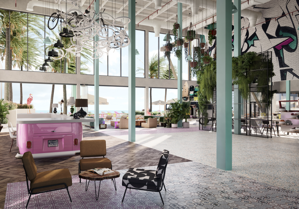 Modern indoor lounge area with large windows, hanging plants, and colorful decor, overlooking a beach with palm trees and flamingo statues.