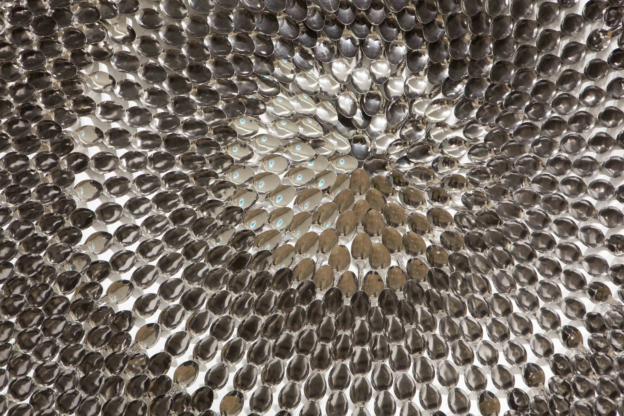 Close-up of a spherical mirror installation with numerous small, shiny, metallic spheres reflecting the surroundings.