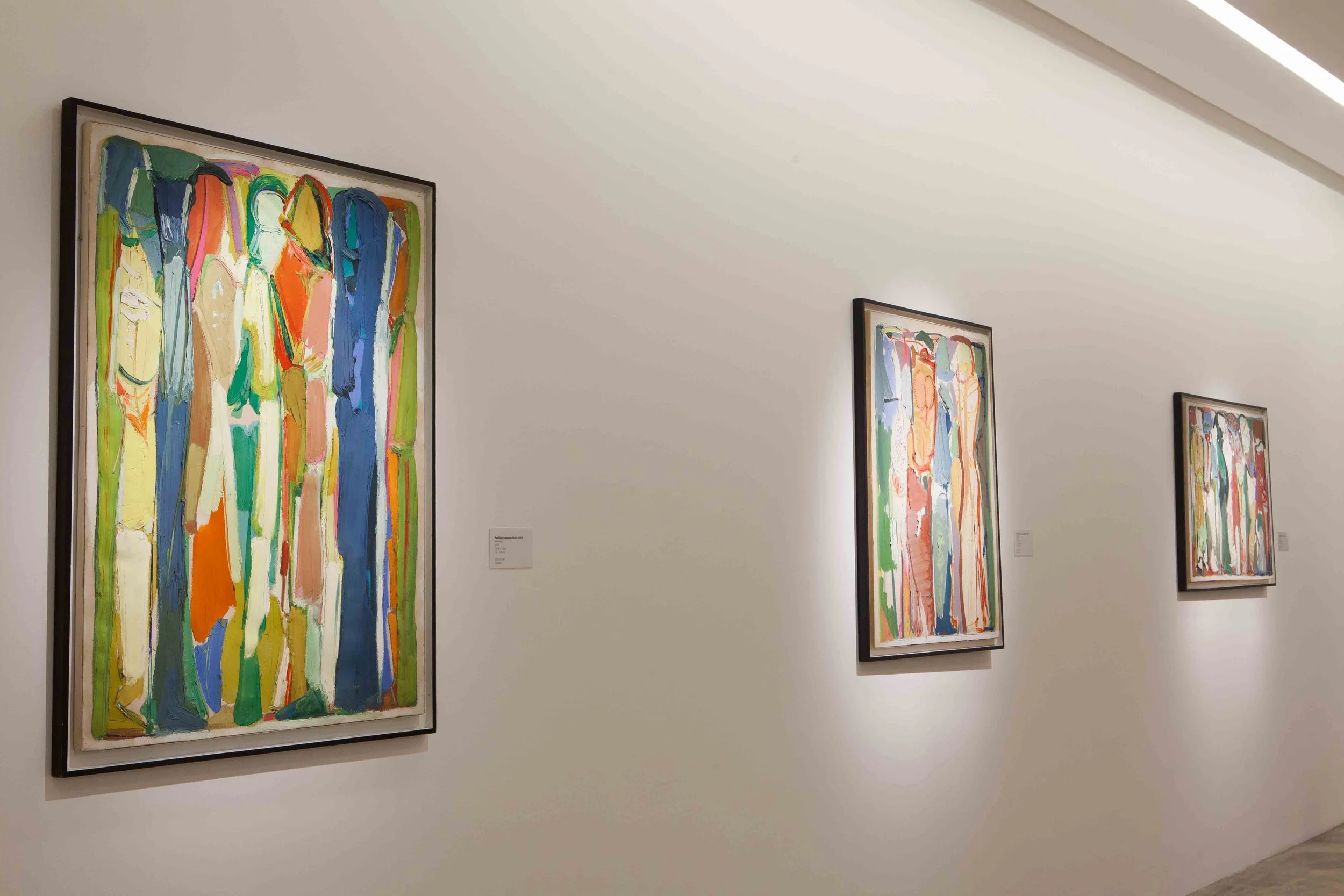 Three colorful abstract paintings hanging on a white gallery wall.