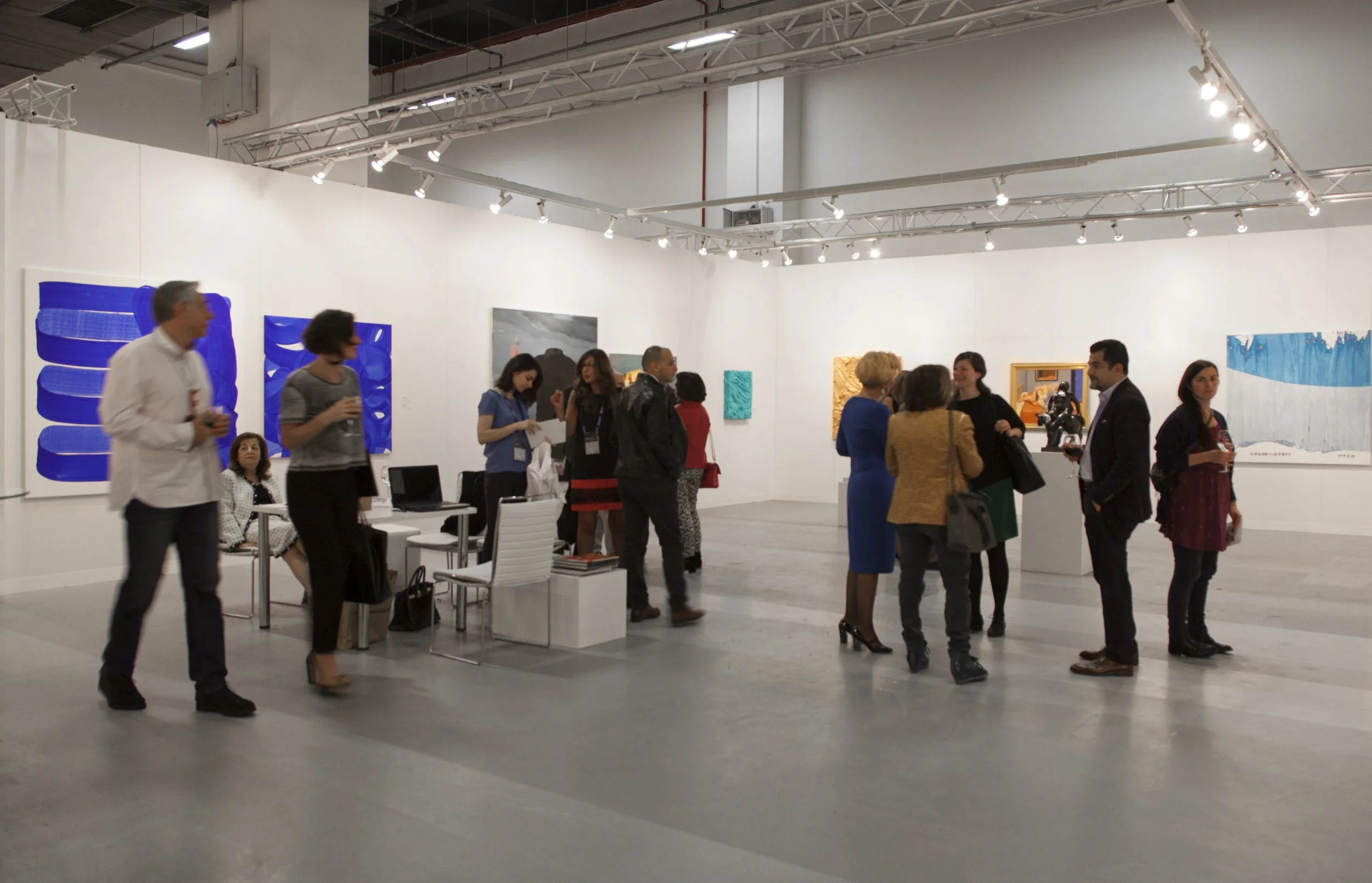 People viewing and discussing artwork in an art gallery with white walls and modern lighting.