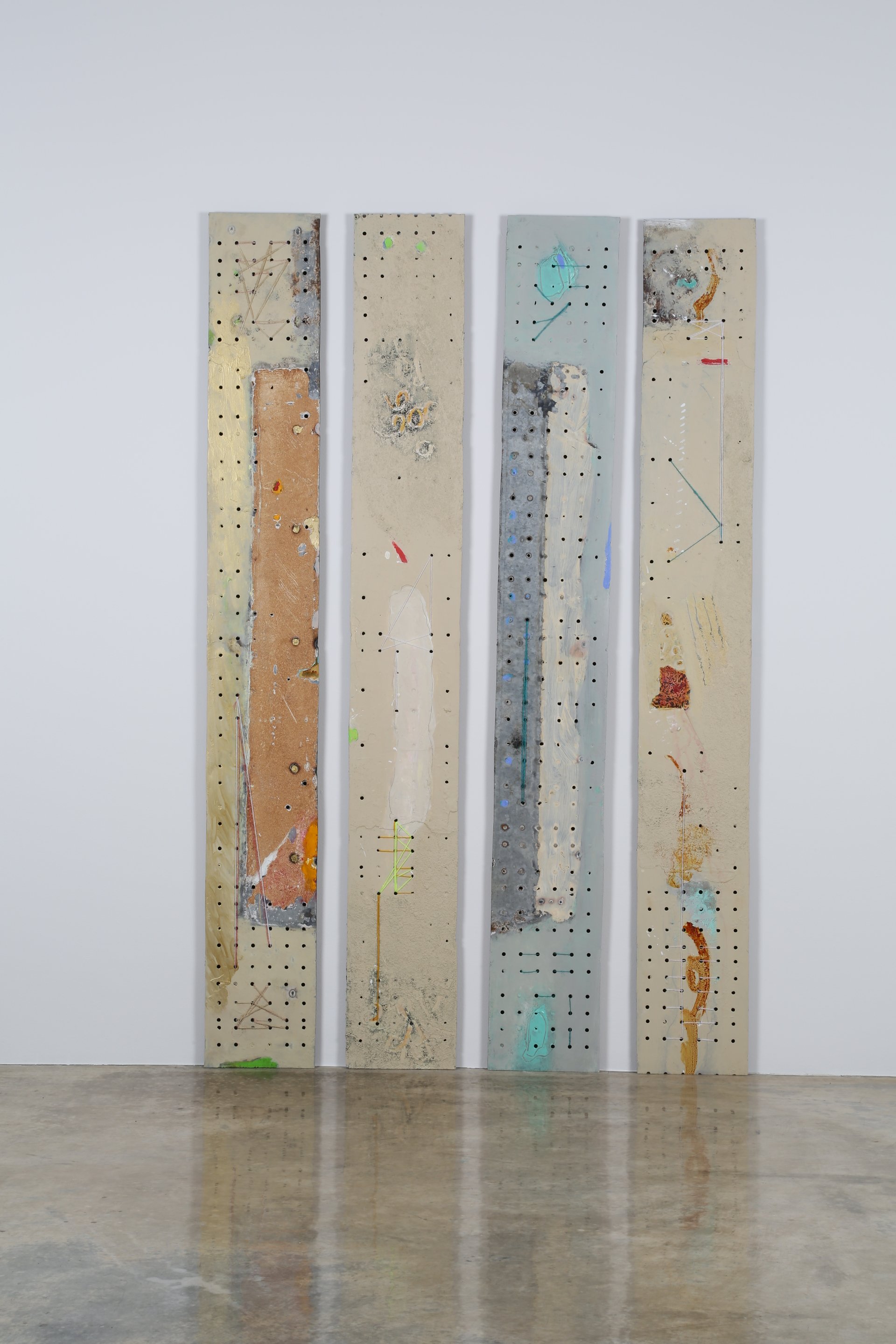 A modern mixed-media abstract artwork consisting of four vertically aligned panels with various textures, colors, and geometric patterns mounted on a white wall.
