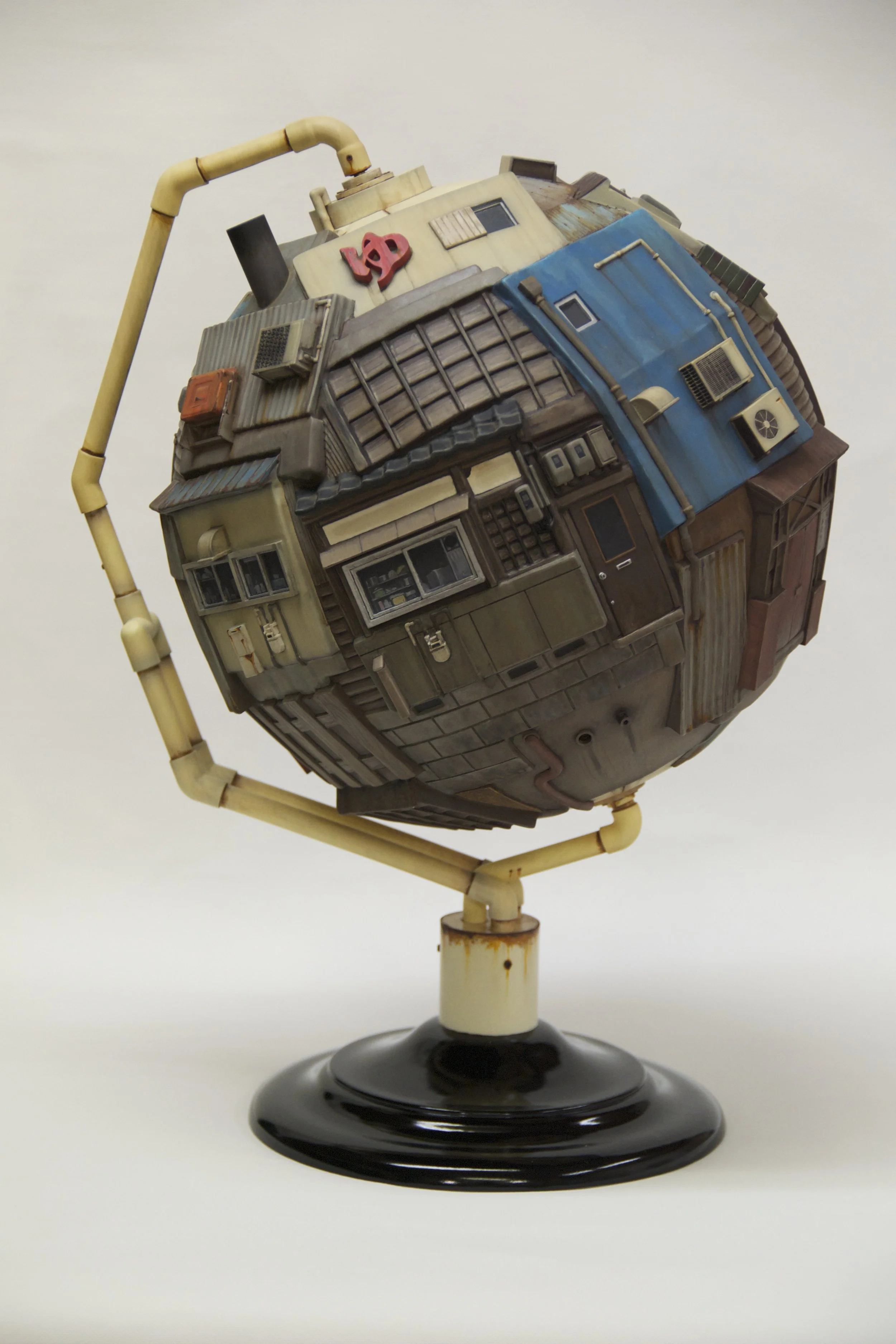A globe sculpture made of miniature buildings and pipes on a black base.