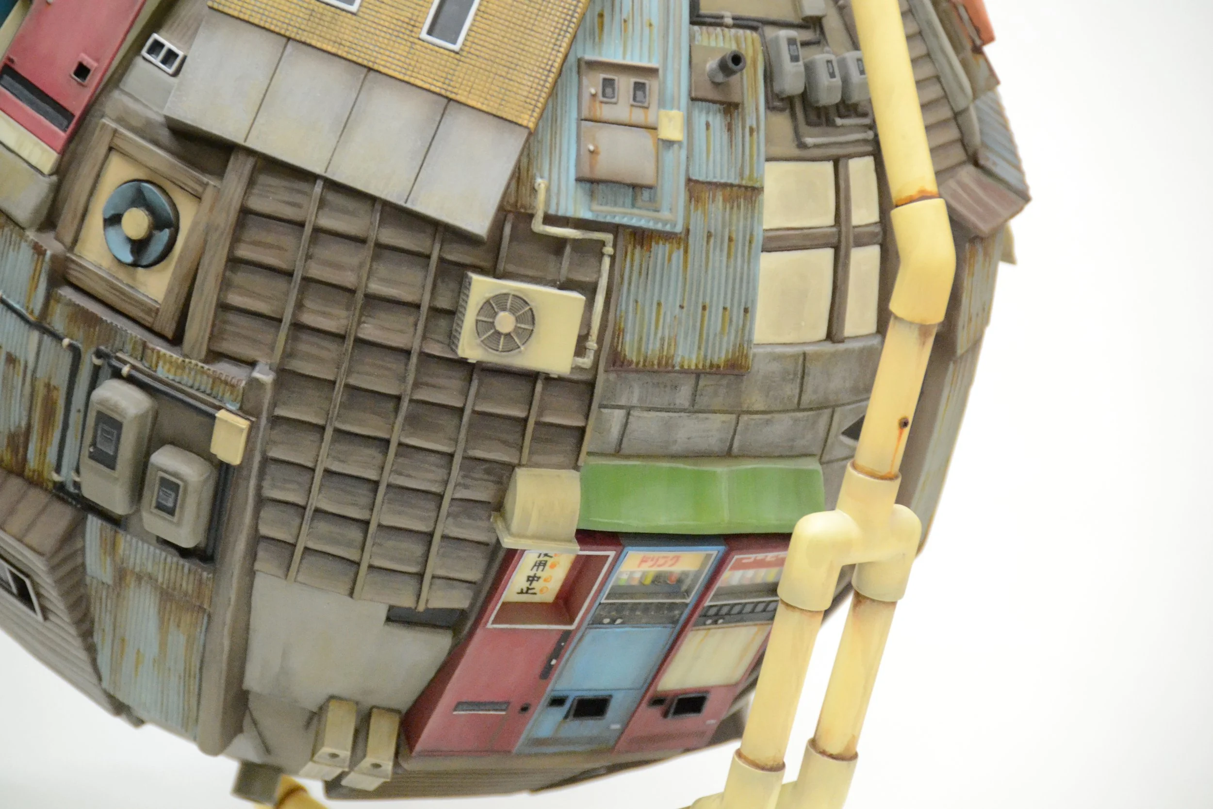 A detailed, close-up view of a miniature model of a spherical building with various mechanical and structural elements like pipes, air conditioning units, and windows.