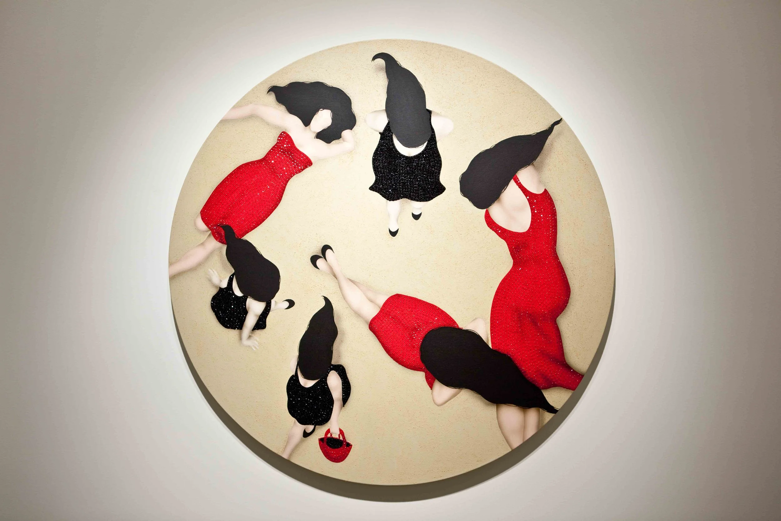 Tops down view of six women in red and black dresses with black hair, standing or walking on a light-colored circular floor in a circular formation.