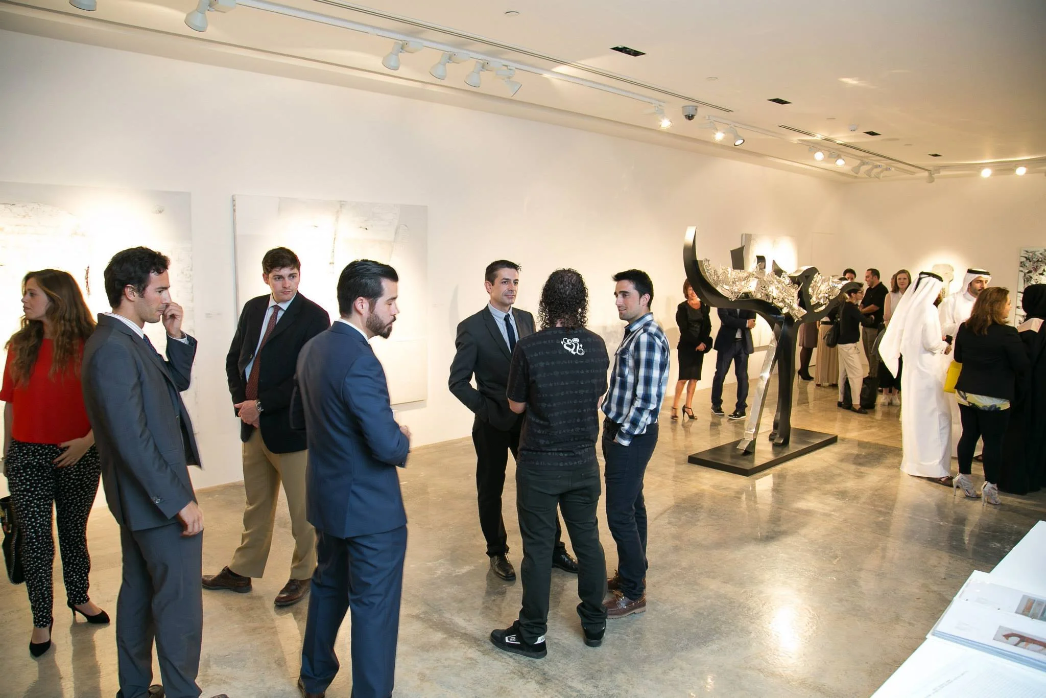 People attending an art gallery or museum exhibition, engaging in conversation and observing artworks and sculptures.