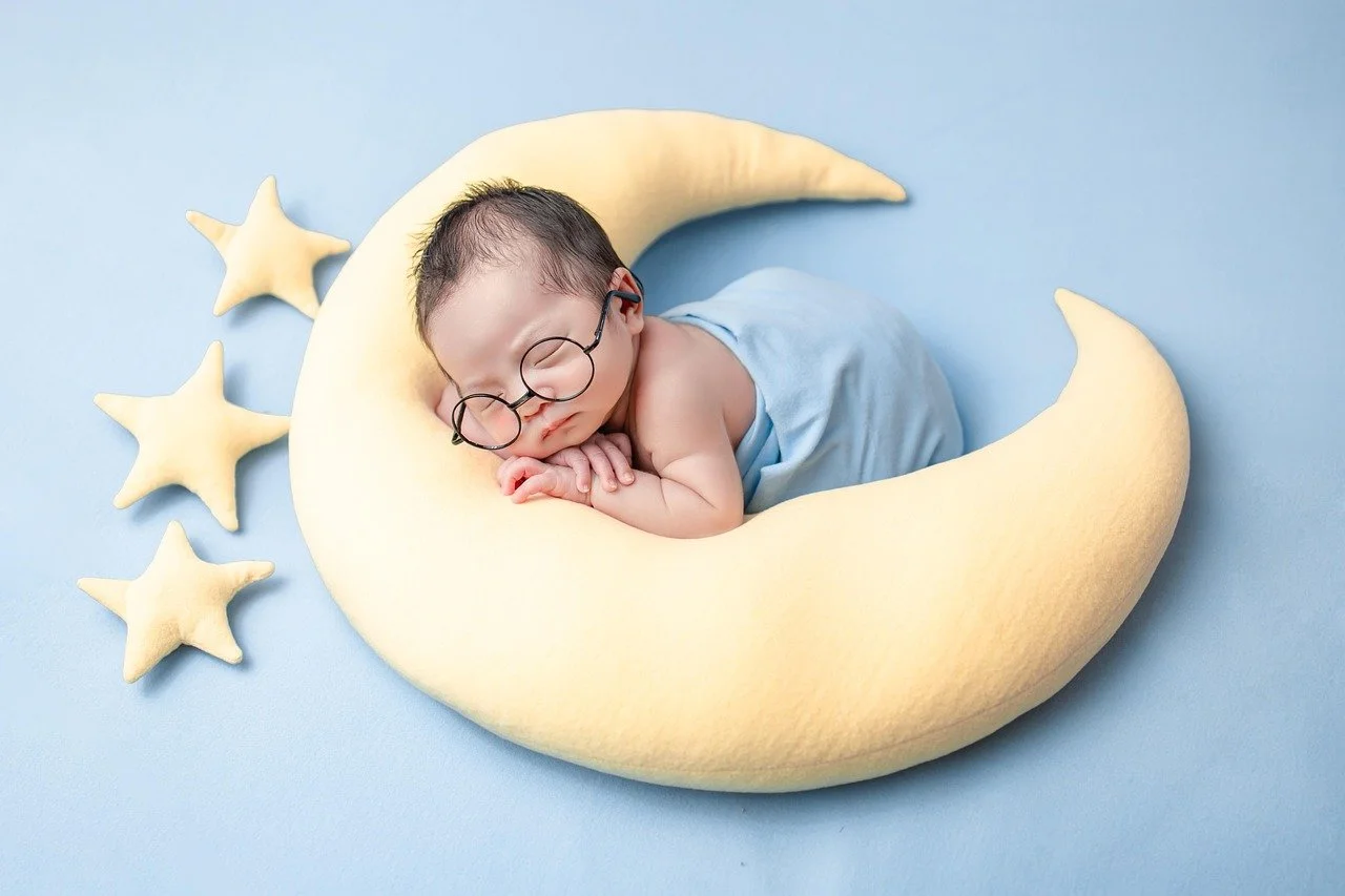 A baby asleep on a crescent moon pillow