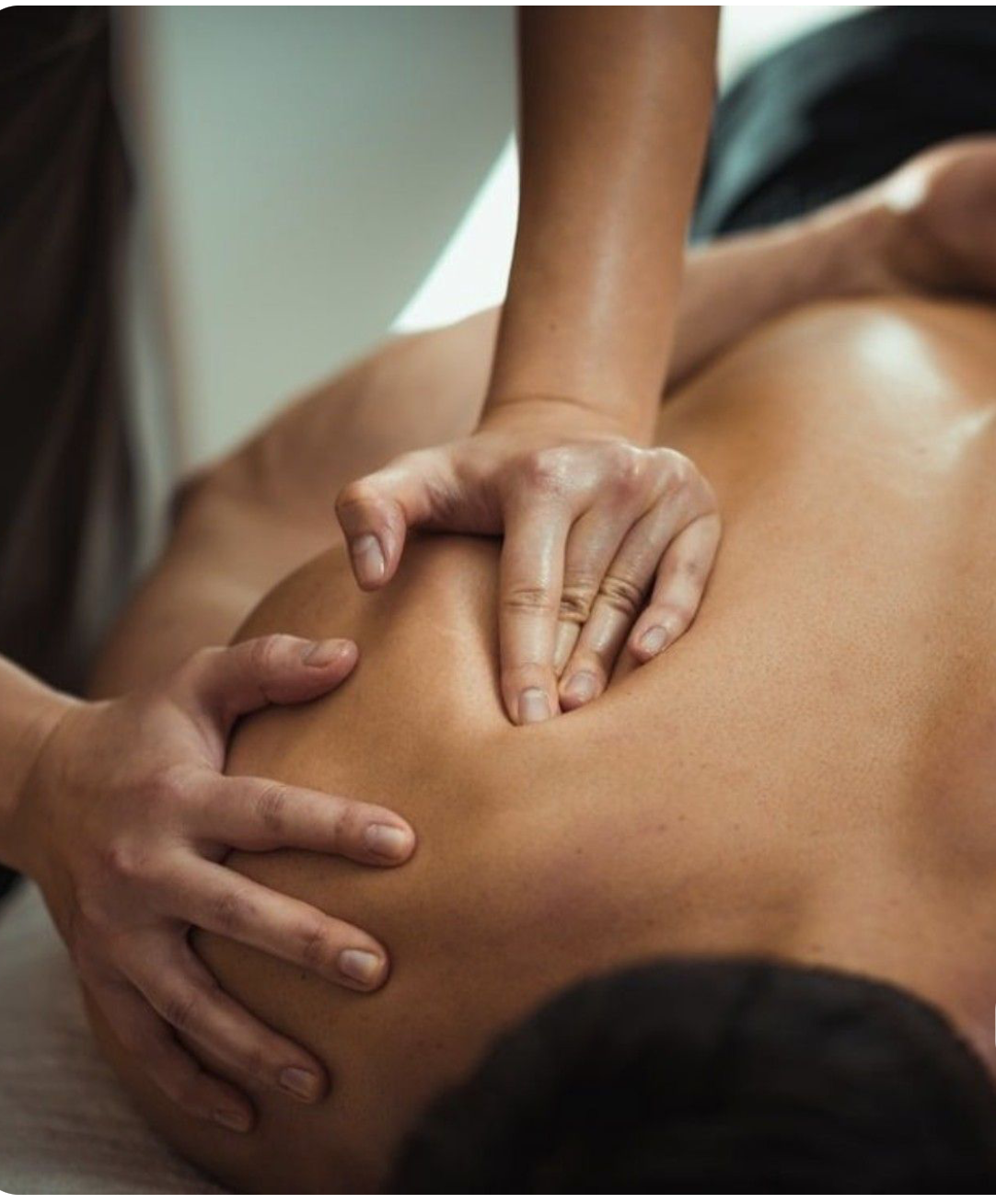 Close-up of a person receiving a massage on their shoulder from a massage therapist.