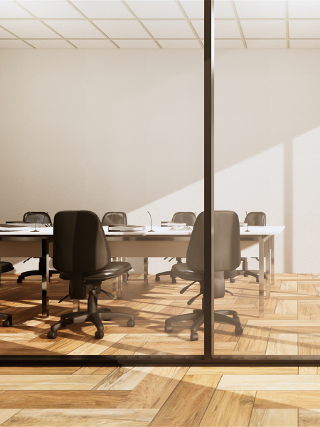 Empty conference room with white table, black chairs, and glass partition in an office setting.