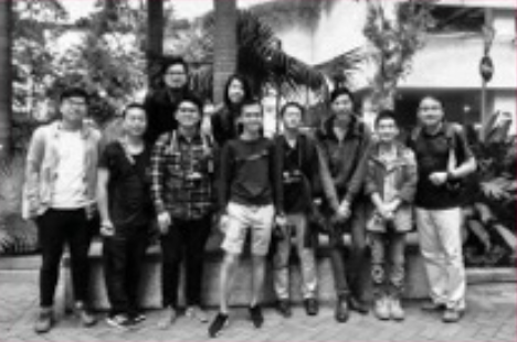 Group of people standing outdoors with palm trees in the background.