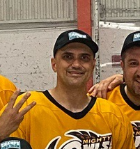 Two men in yellow sports jerseys and black caps smiling at a hockey game