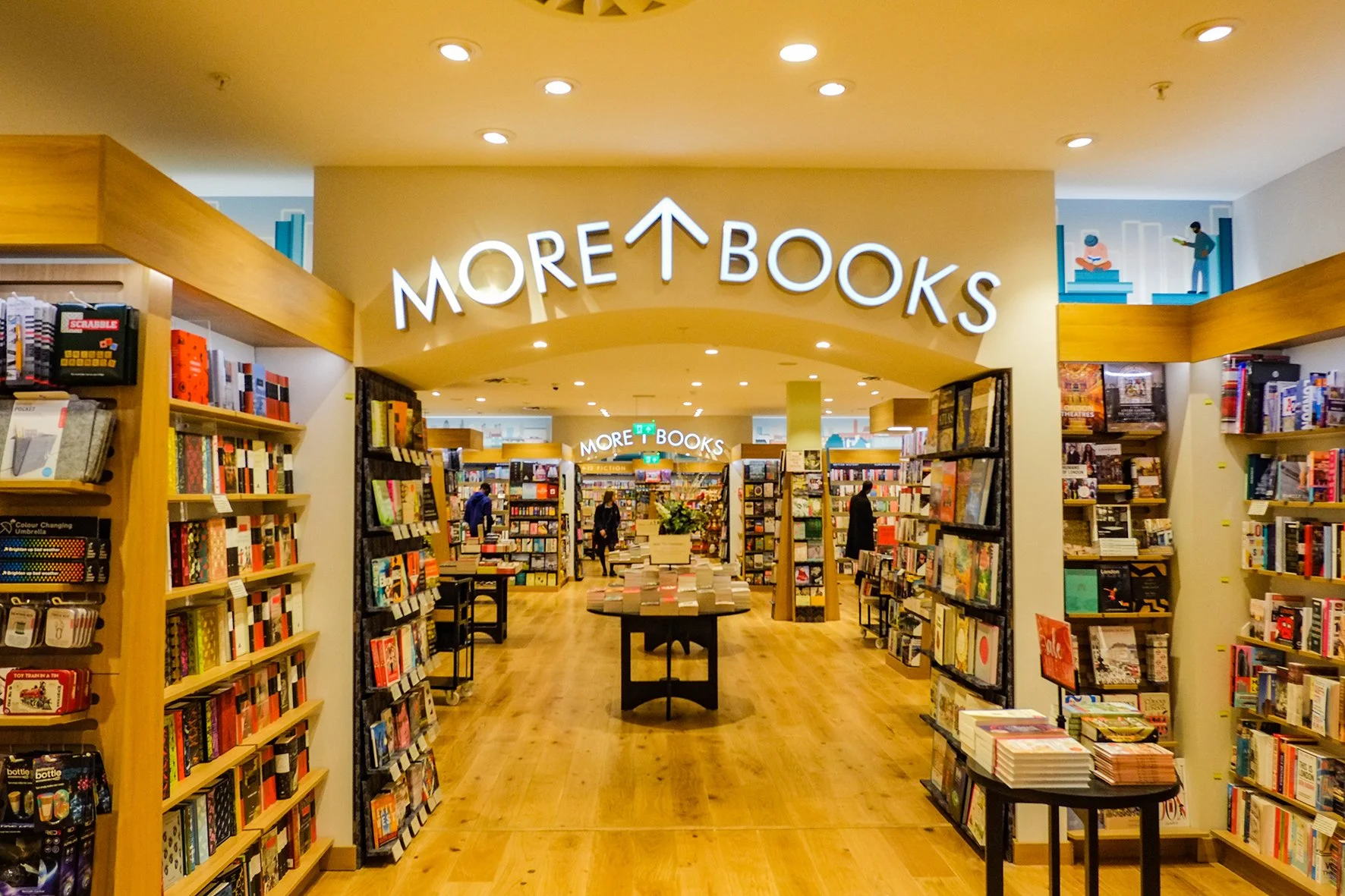 Entrance to a bookstore with a sign that reads 'MORE T BOOKS' and shelves filled with books on both sides.