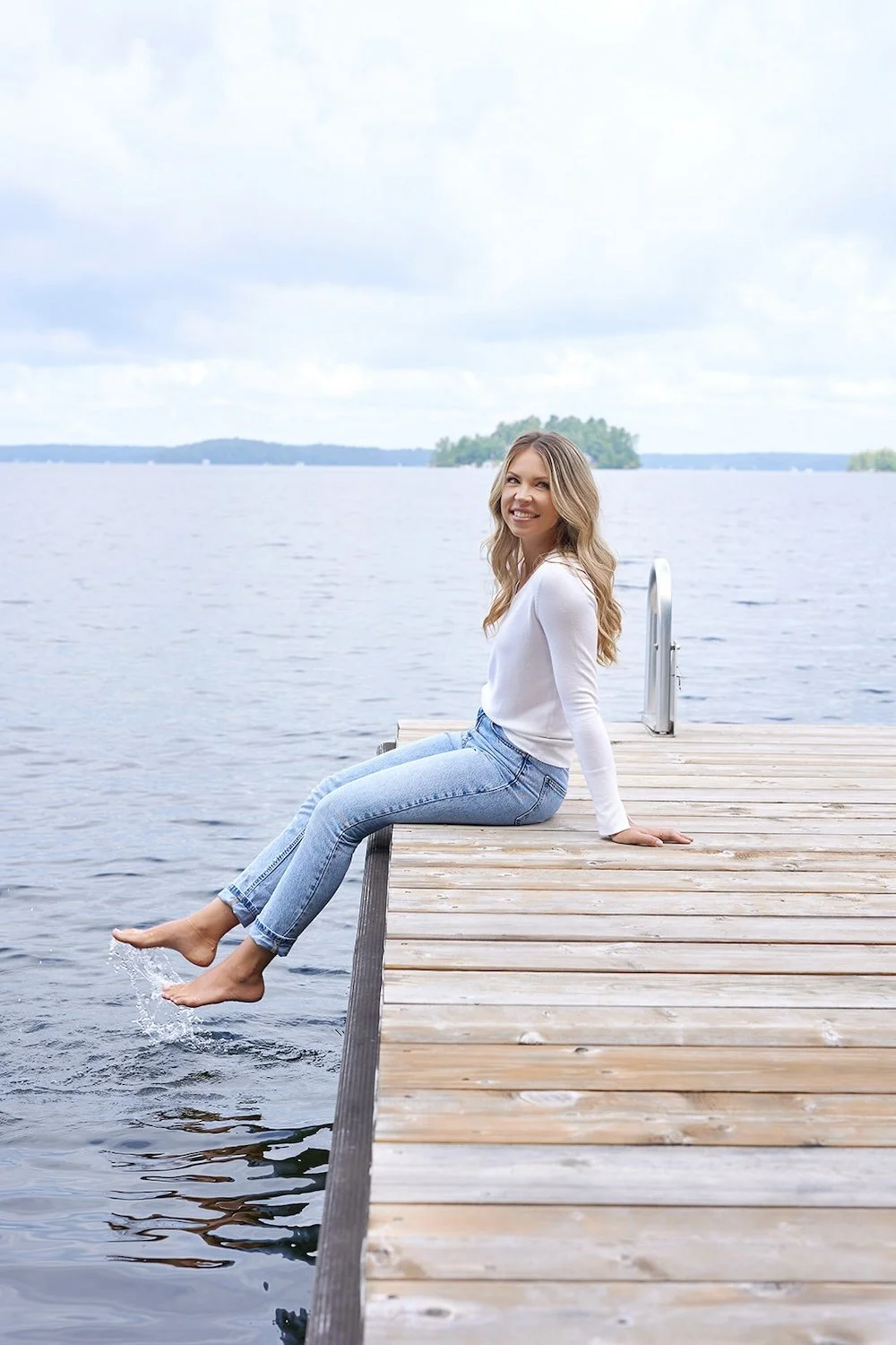 Gini Kelly, Muskoka real estate agent, sitting on a lake dock in Muskoka Lakes, Ontario.