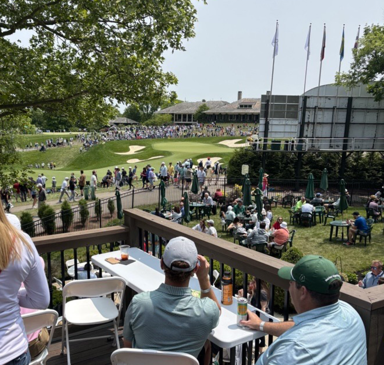 People watching a golf tournament from a balcony at a golf course during daytime