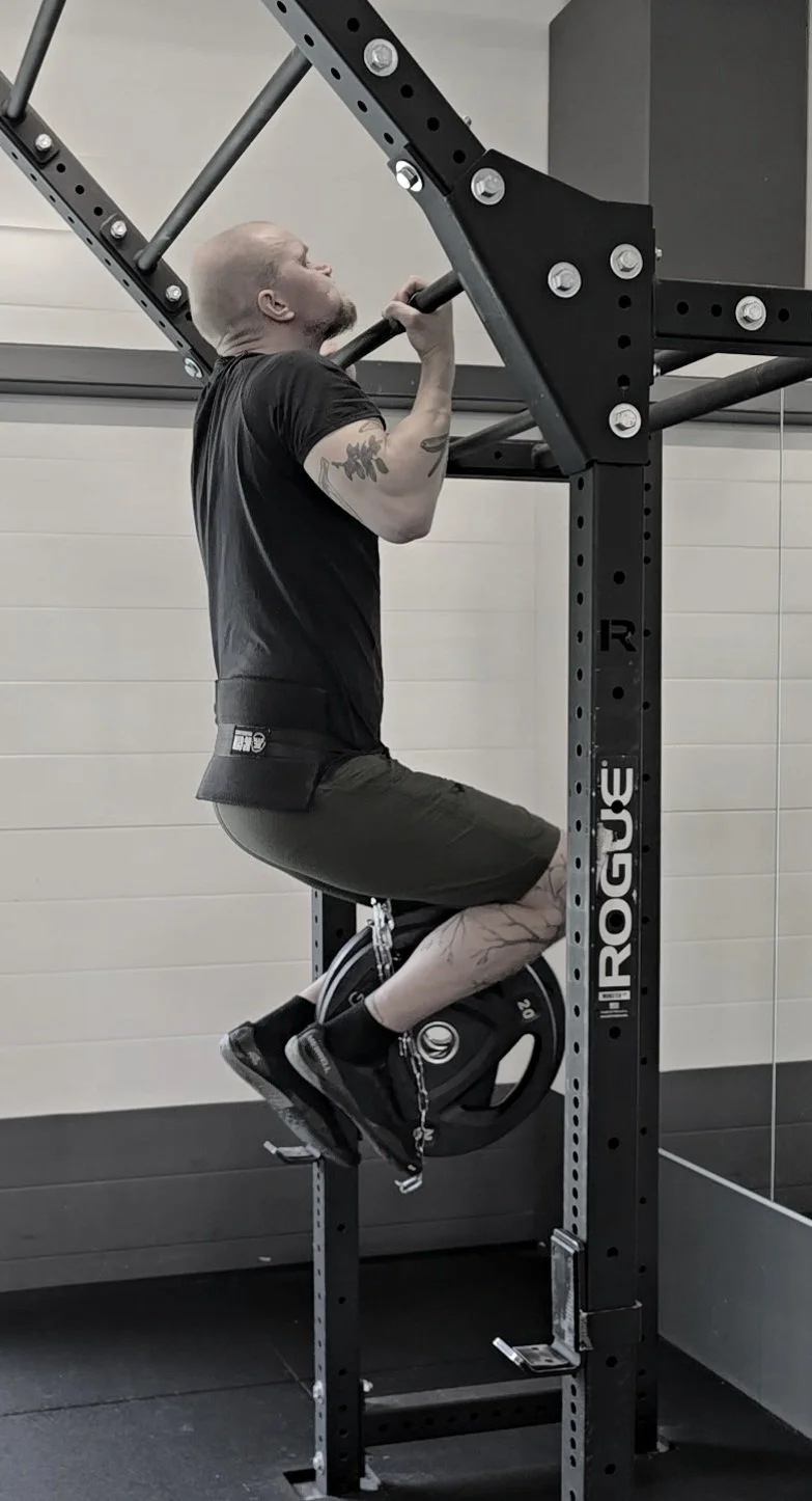 Mies tekee leuanvetoa 45kg:n lisäpainolla.