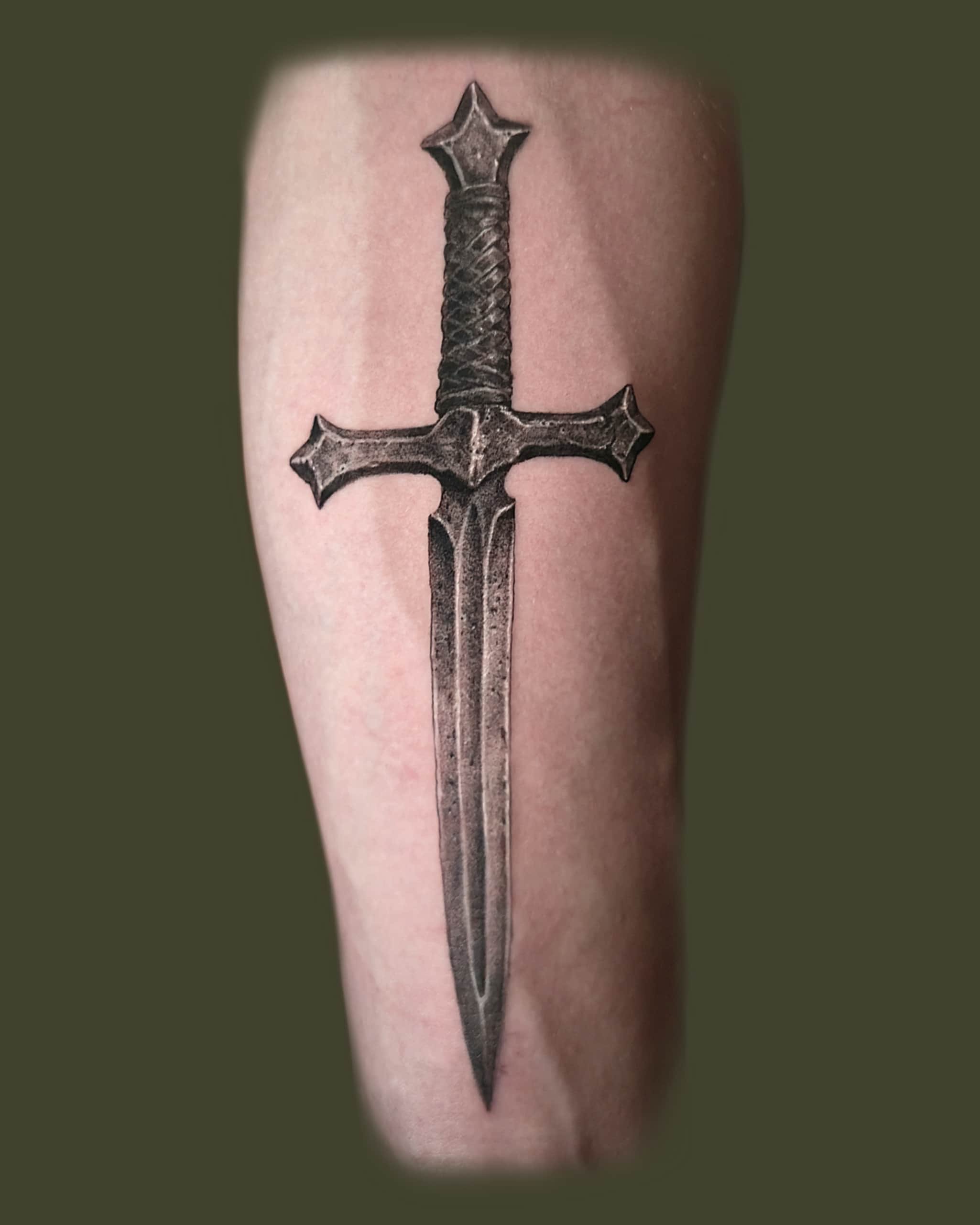 Trealistinen tatuointi, jossa on tikari. Miekka on tummasävyinen ja sen terä on pitkänomainen.