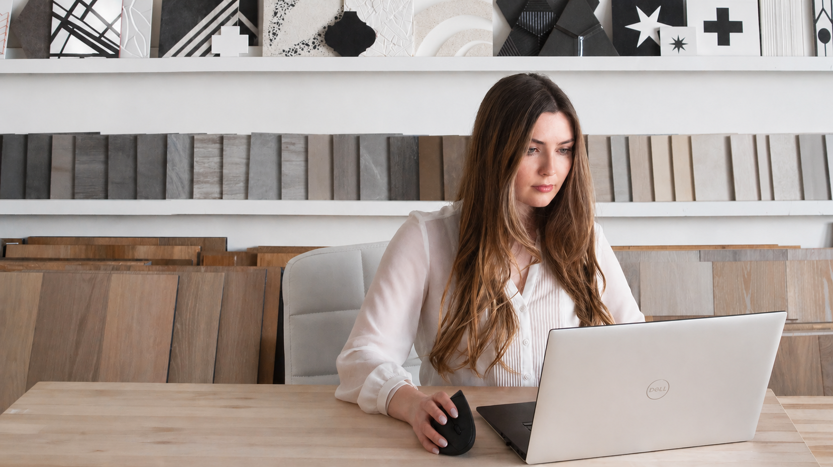 Annie Koepke, TECHNICAL DESIGN LEAD, working on her computer with luxury tile samples presented on the wall behind her