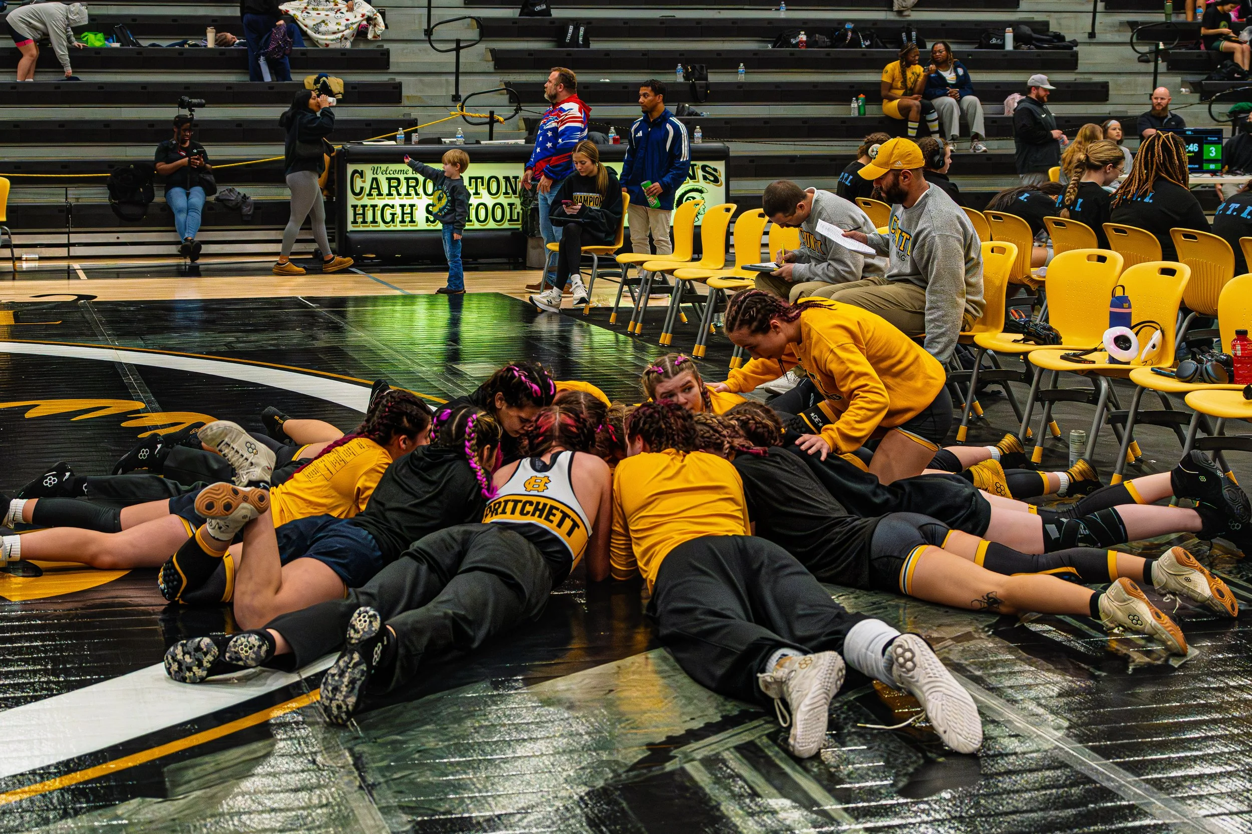 High school girls volleyball team huddled together on the court during a game.