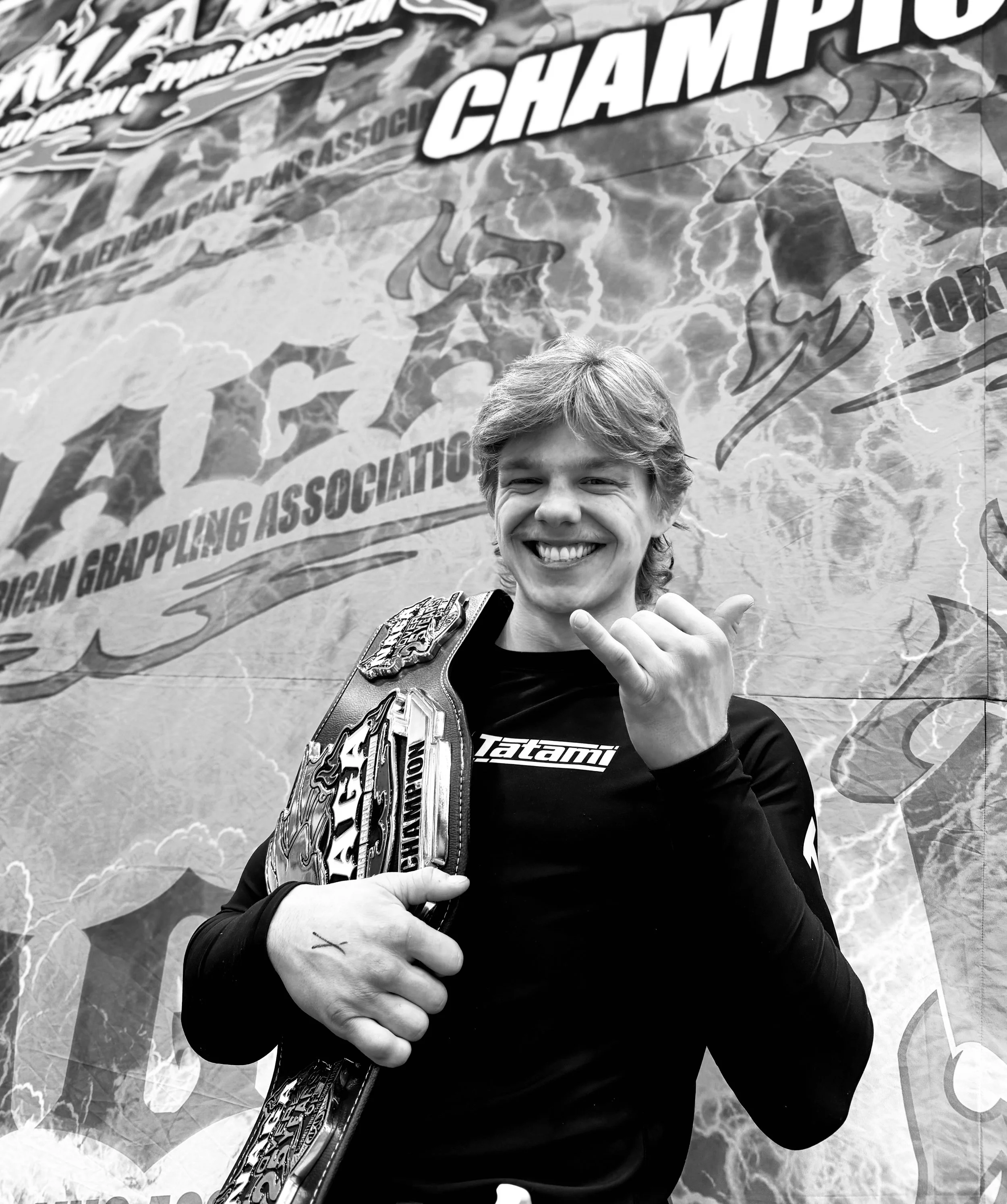 Jiu-Jitsu competitor holding a championship belt after a submission grappling event.