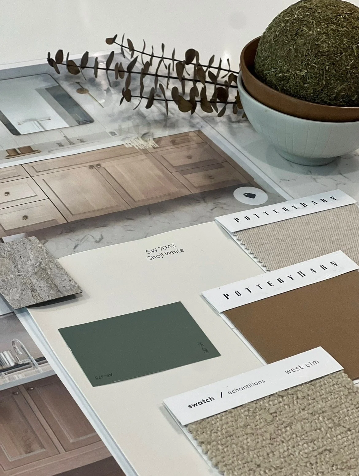 A color palette and fabric swatch samples on a table with kitchen cabinet and countertop samples in the background.