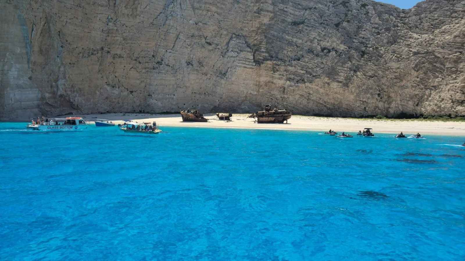 plages avec des bateaux et un vieux navire échoué devant une falaise rocheuse