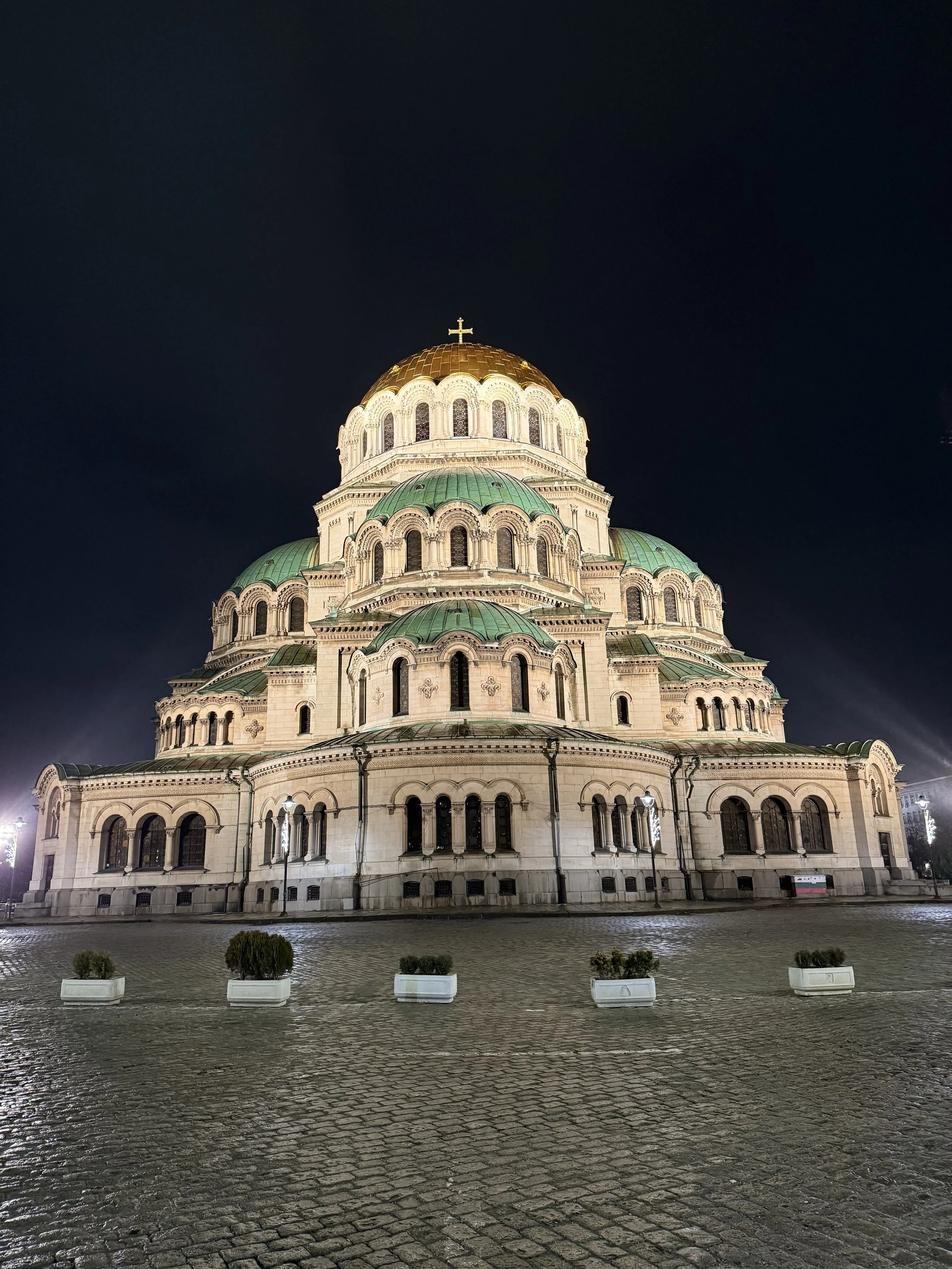 Une église orthodoxe avec une grande coupole en or, éclairée la nuit, avec un ciel sombre en arrière-plan.