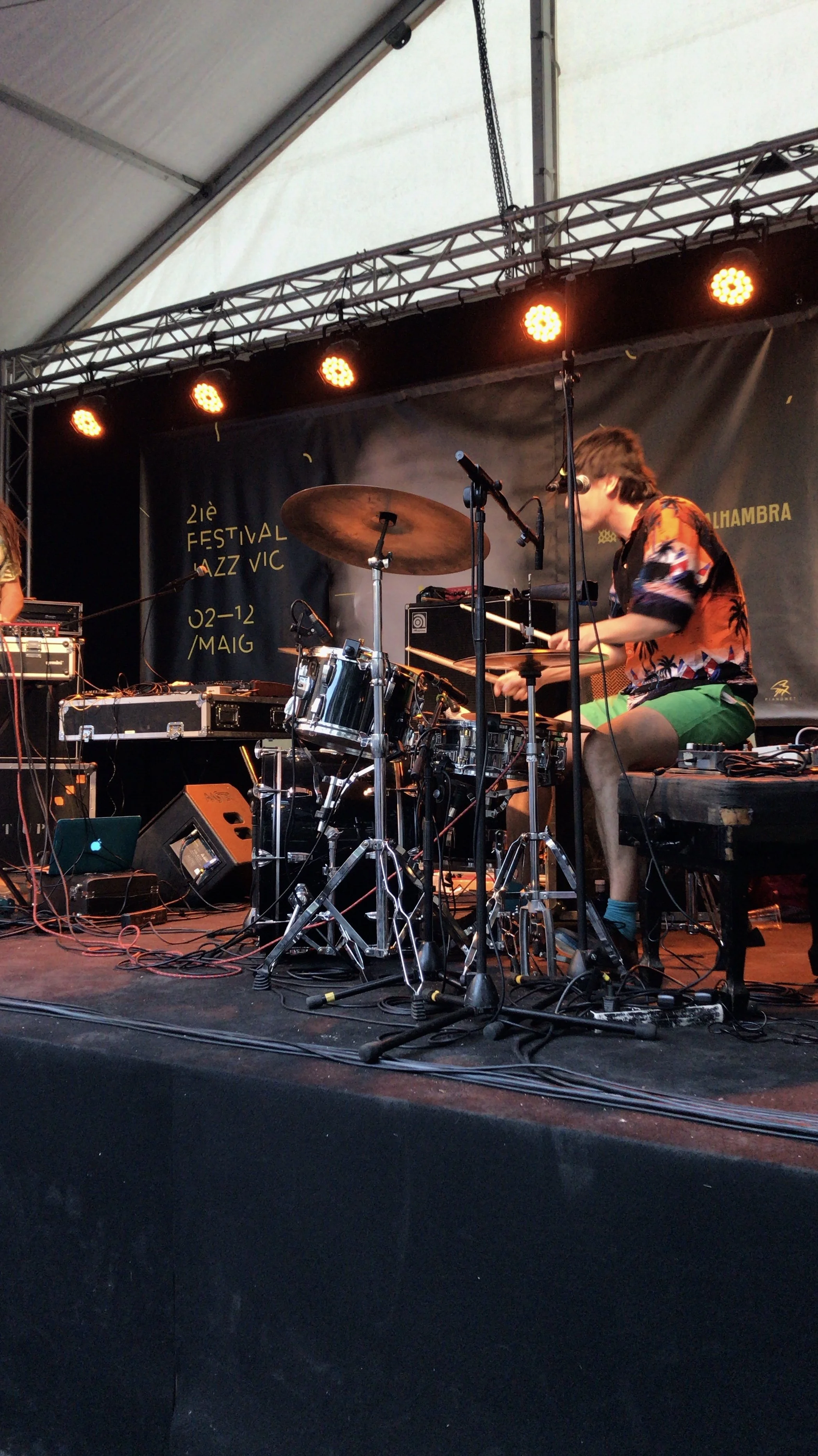 Concerts. Musician playing electronic drums on stage with orange lighting at the Festival La Jazz Vic, in Spain, in May.