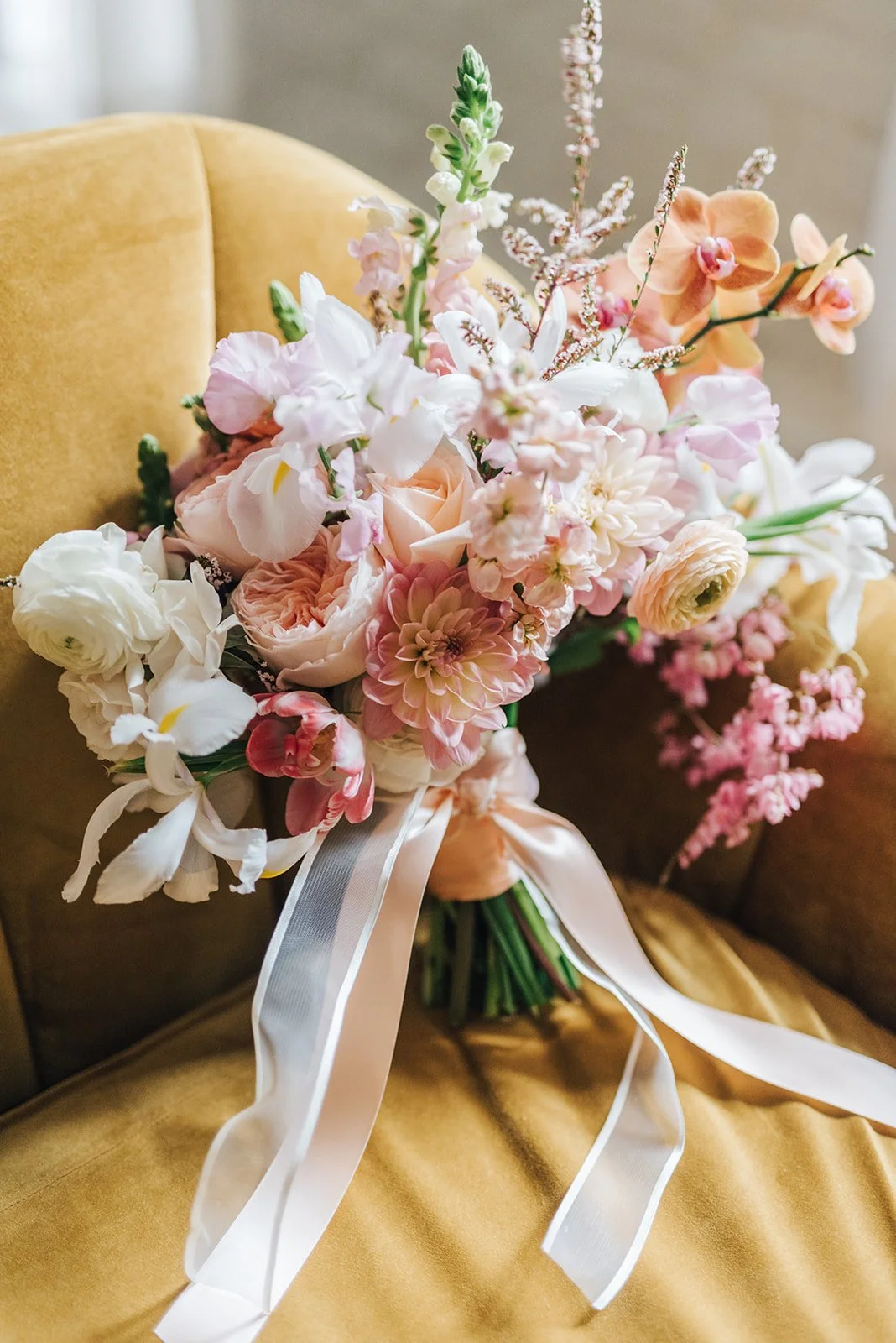 A bouquet of pink and white flowers resting on a yellow upholstered chair.