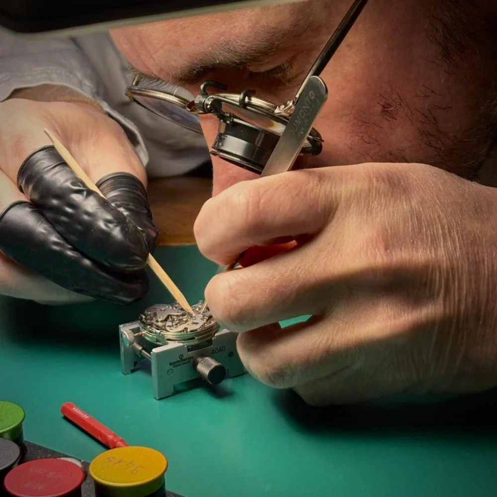 Un horloger ajuste un mécanisme de montre avec des outils précis.