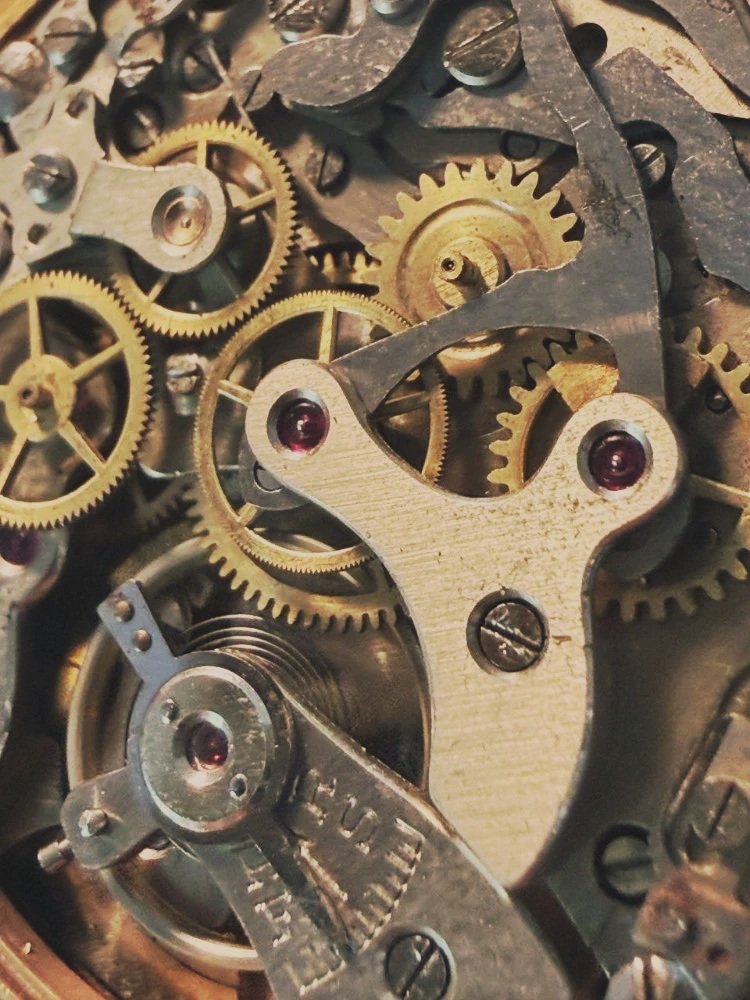 Mécanisme montre horloger, engrenages en métal, vis et pièces en mouvement.
