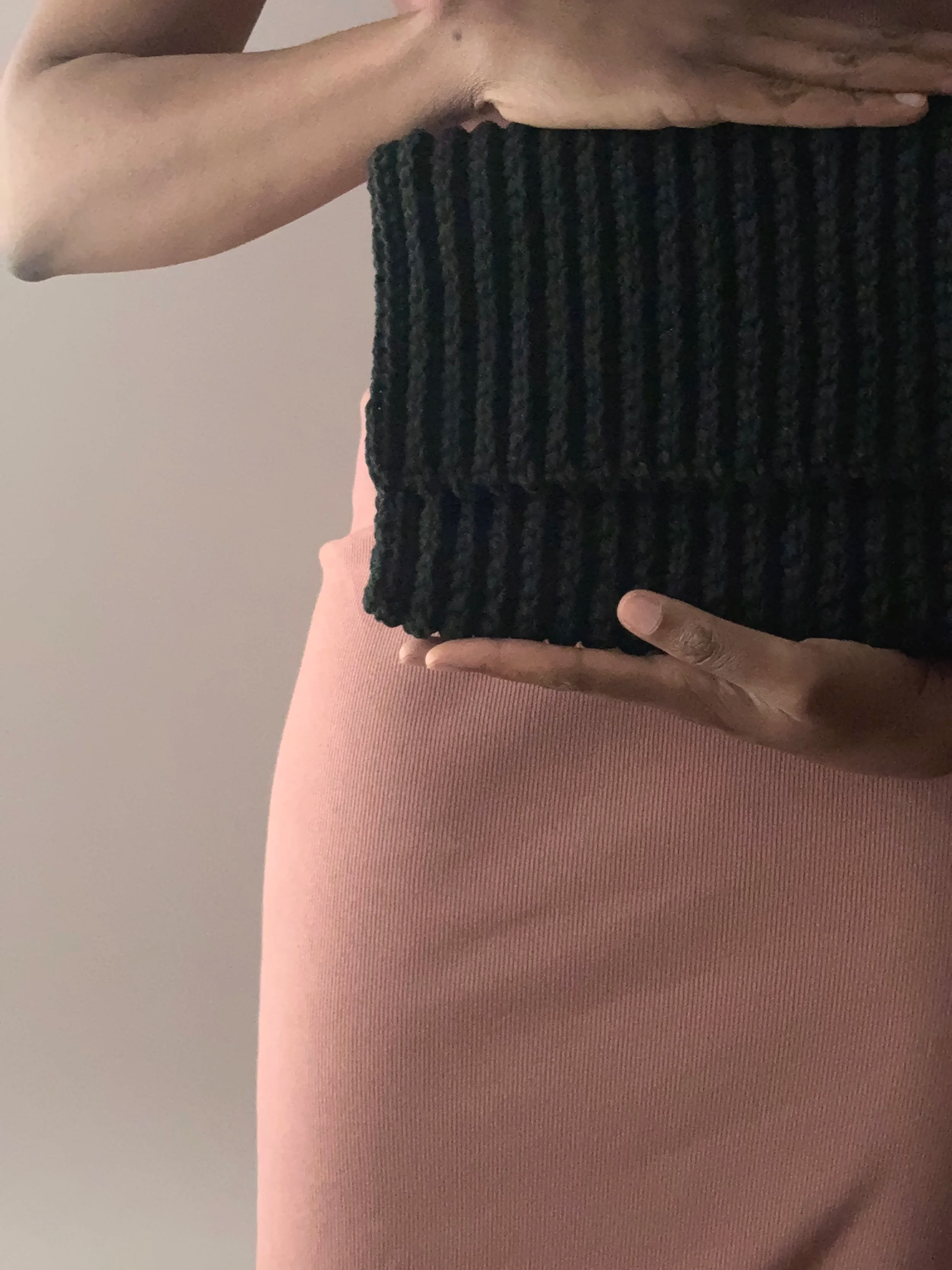 Le haut du corps d'une personne tenant un sac au crochet noir avec une robe rose.