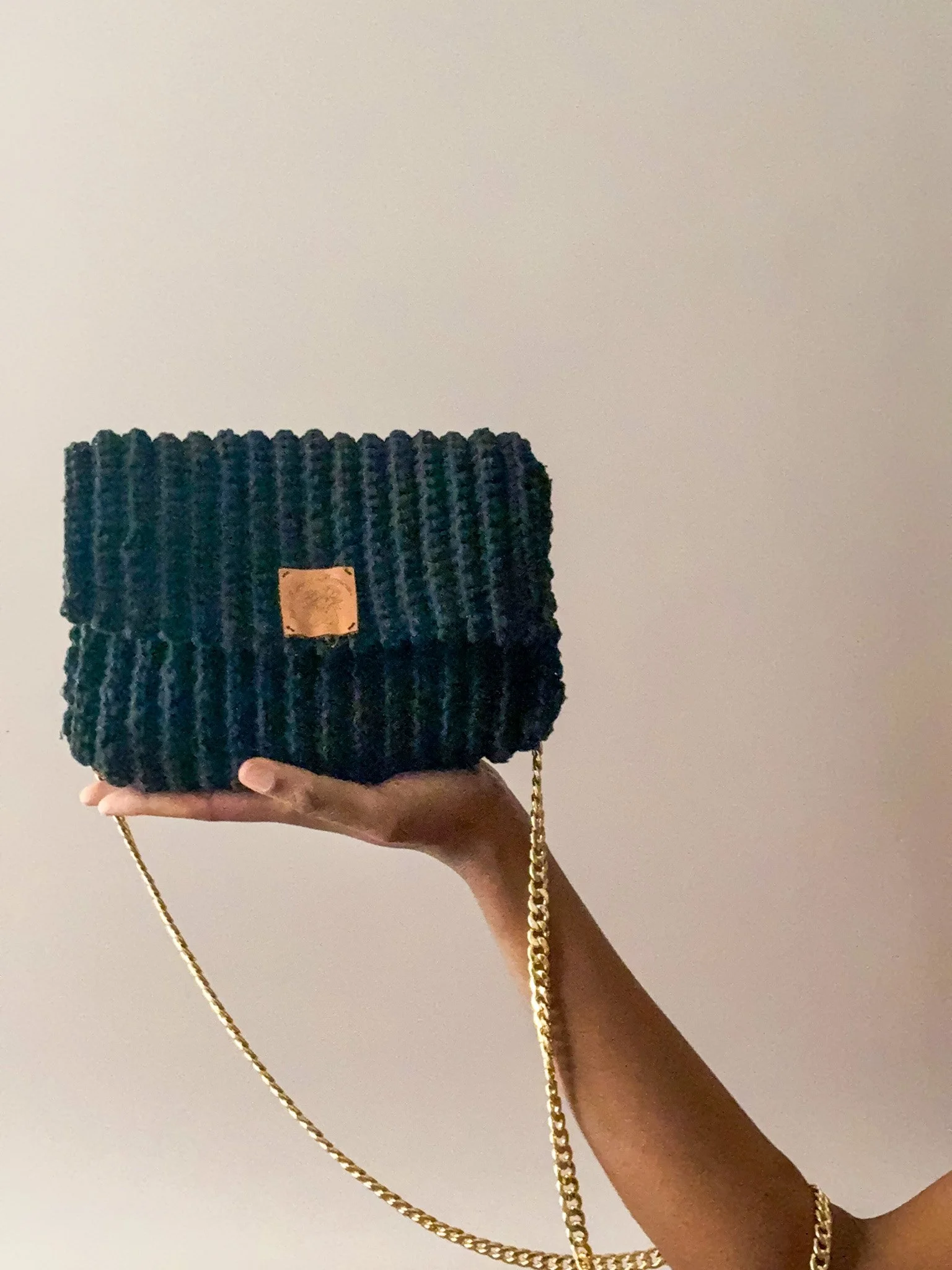 Main tenant une petite sac en velours noir avec une chaîne dorée