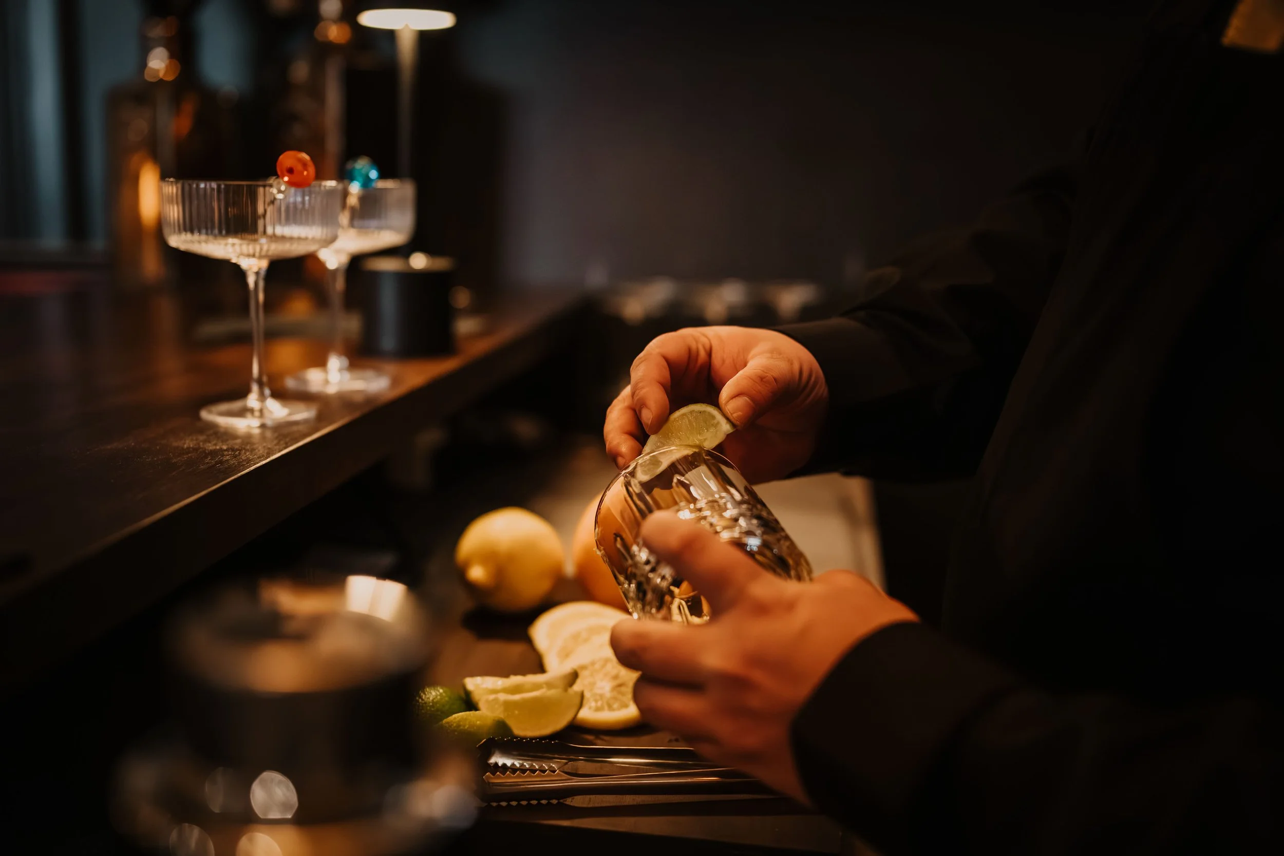 Bartender preparing a cocktail with fresh citrus at the bar inside Sir Sanford Loft On Main in Collingwood