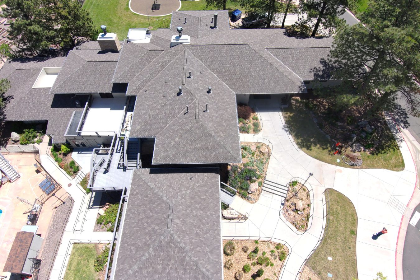 Aerial view of a multi-building residential complex in Colorado with a landscaped courtyard, sidewalks, trees, and parking area.