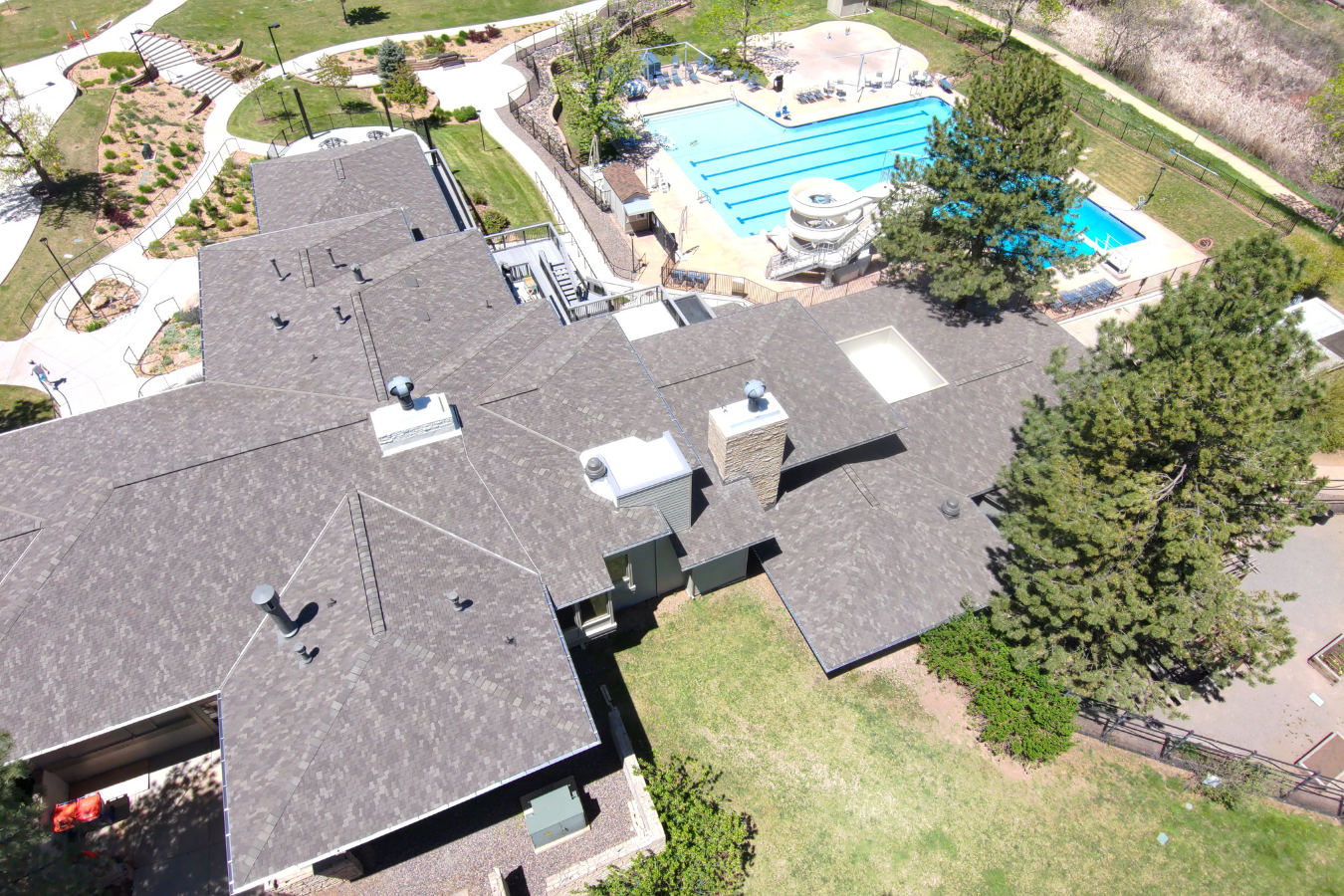 Aerial view of a residential roof in Colorado showing rooftops, a swimming pool, and surrounding greenery.