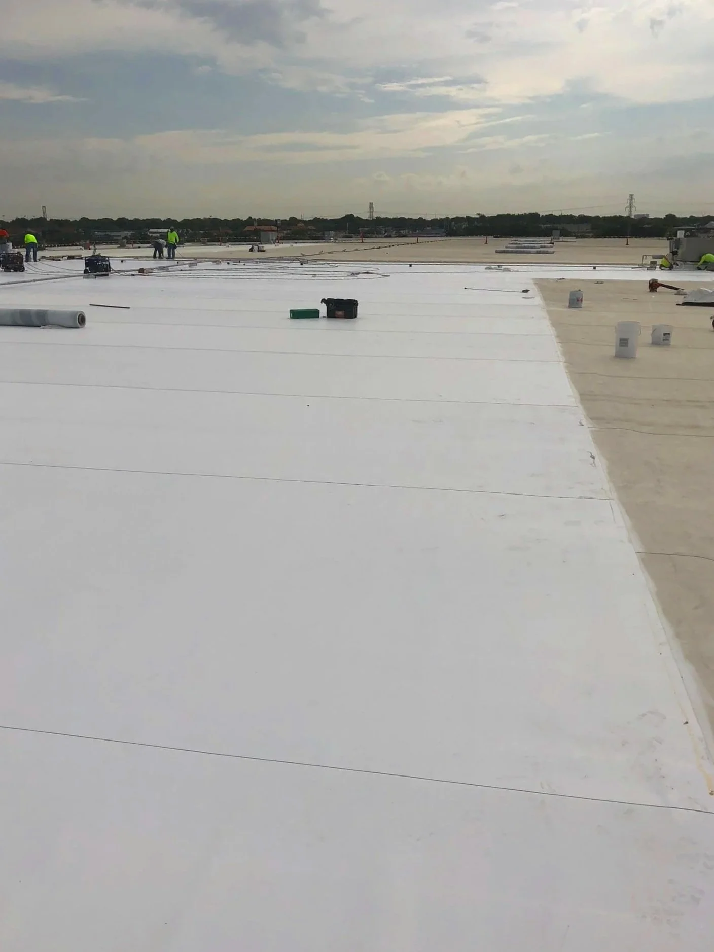 A flat white commercial rooftop under a partly cloudy sky.
