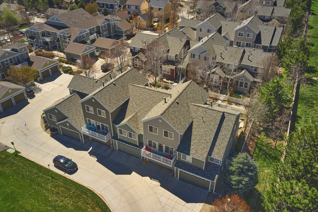 An aerial view of a residential neighborhood with townhouses and other houses, surrounded by trees and greenery.